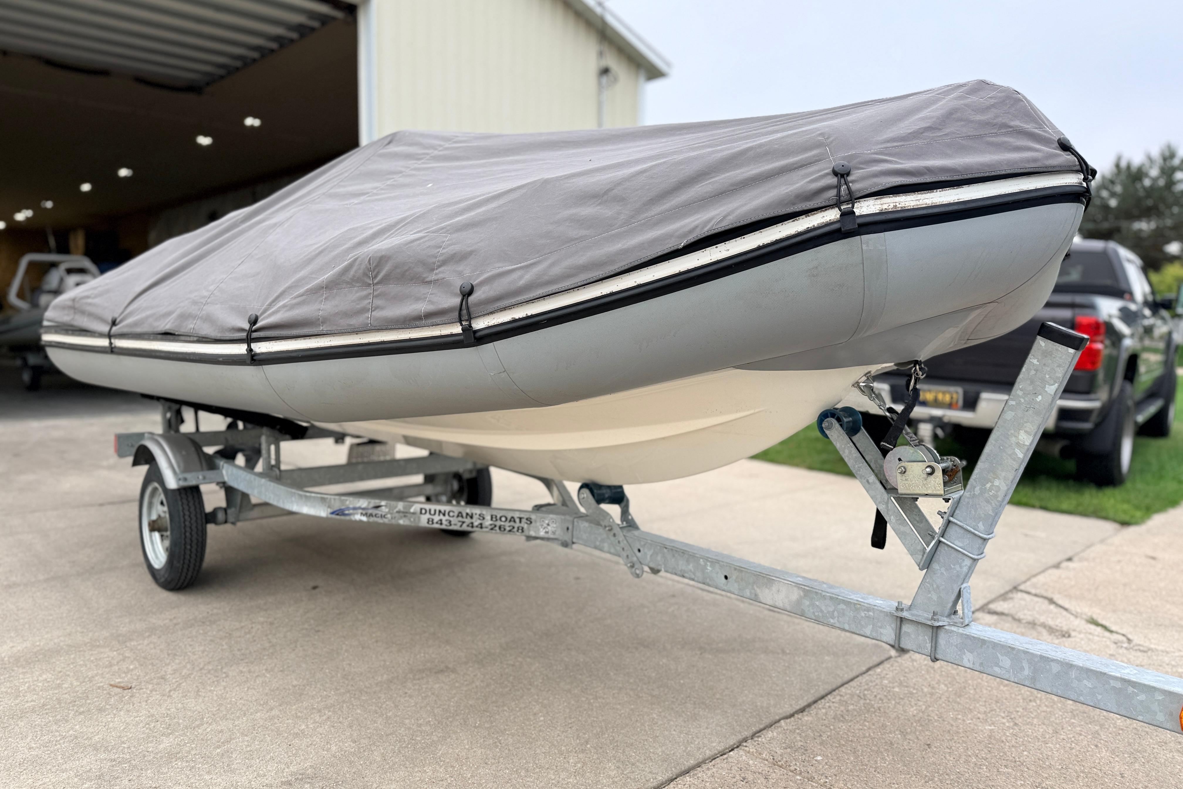 2014 Zodiac Pro Classic 420 boat covered on trailer, parked outside a garage.