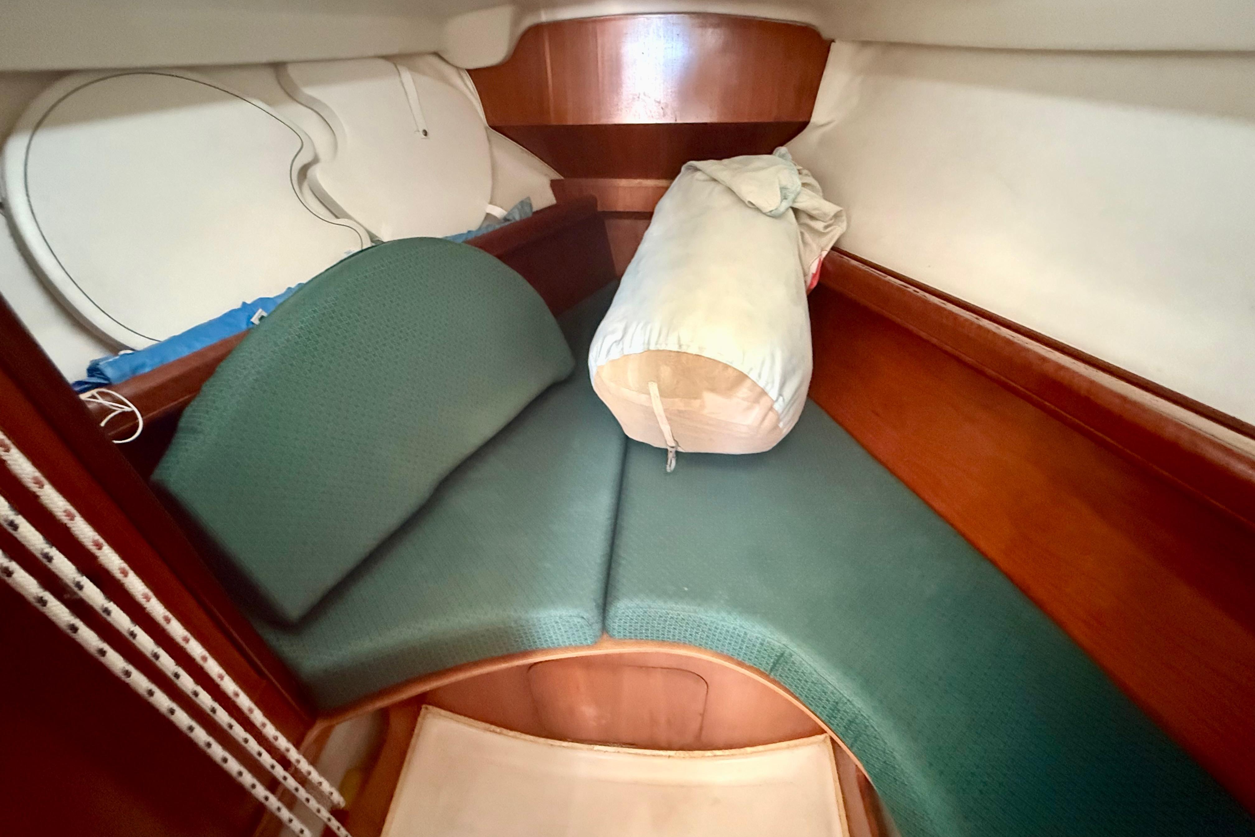 Interior cabin of 2002 Beneteau Oceanis Clipper 311 with green cushions and wooden finish.