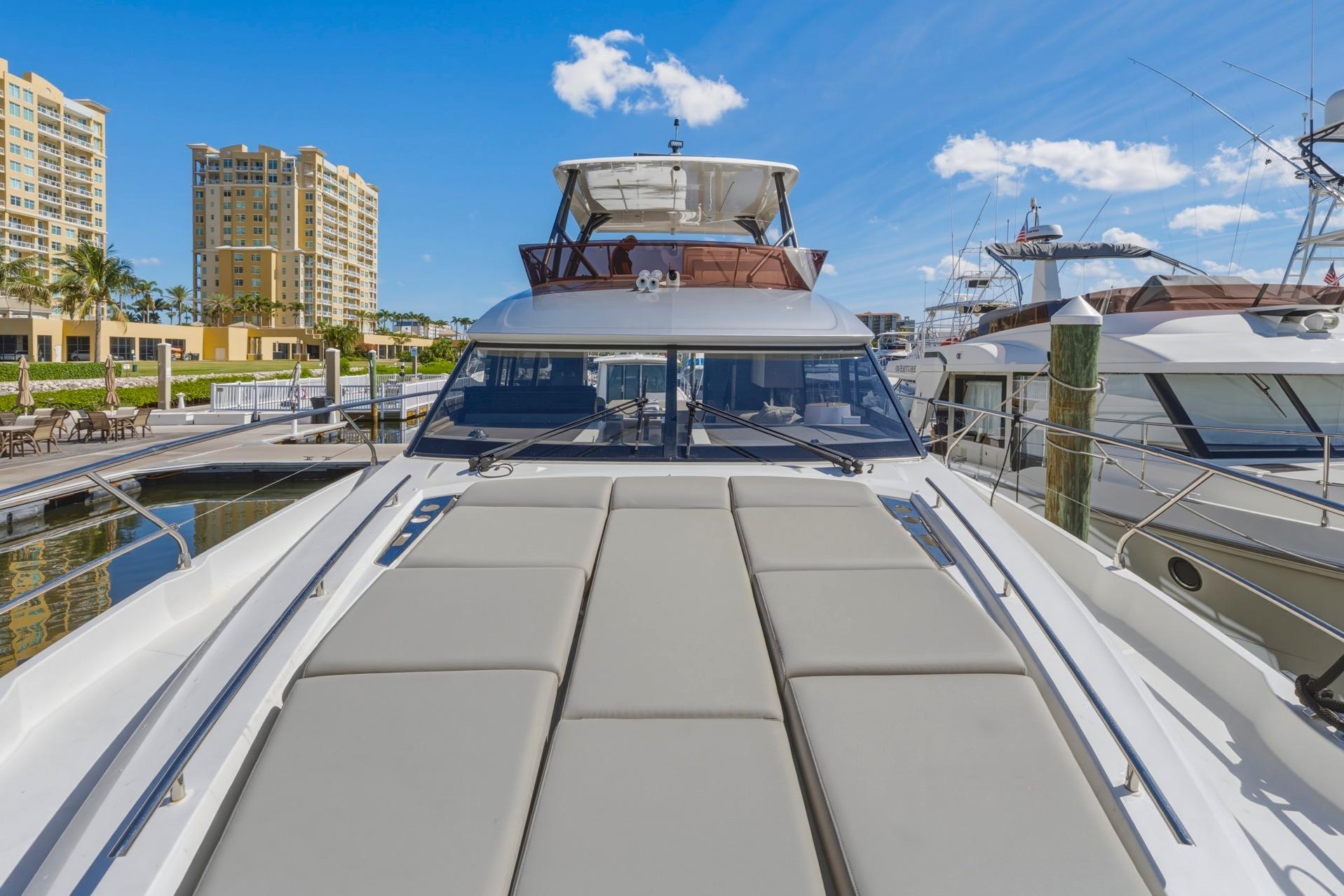 Luxury 2022 Prestige 520 yacht docked at marina under clear blue sky.