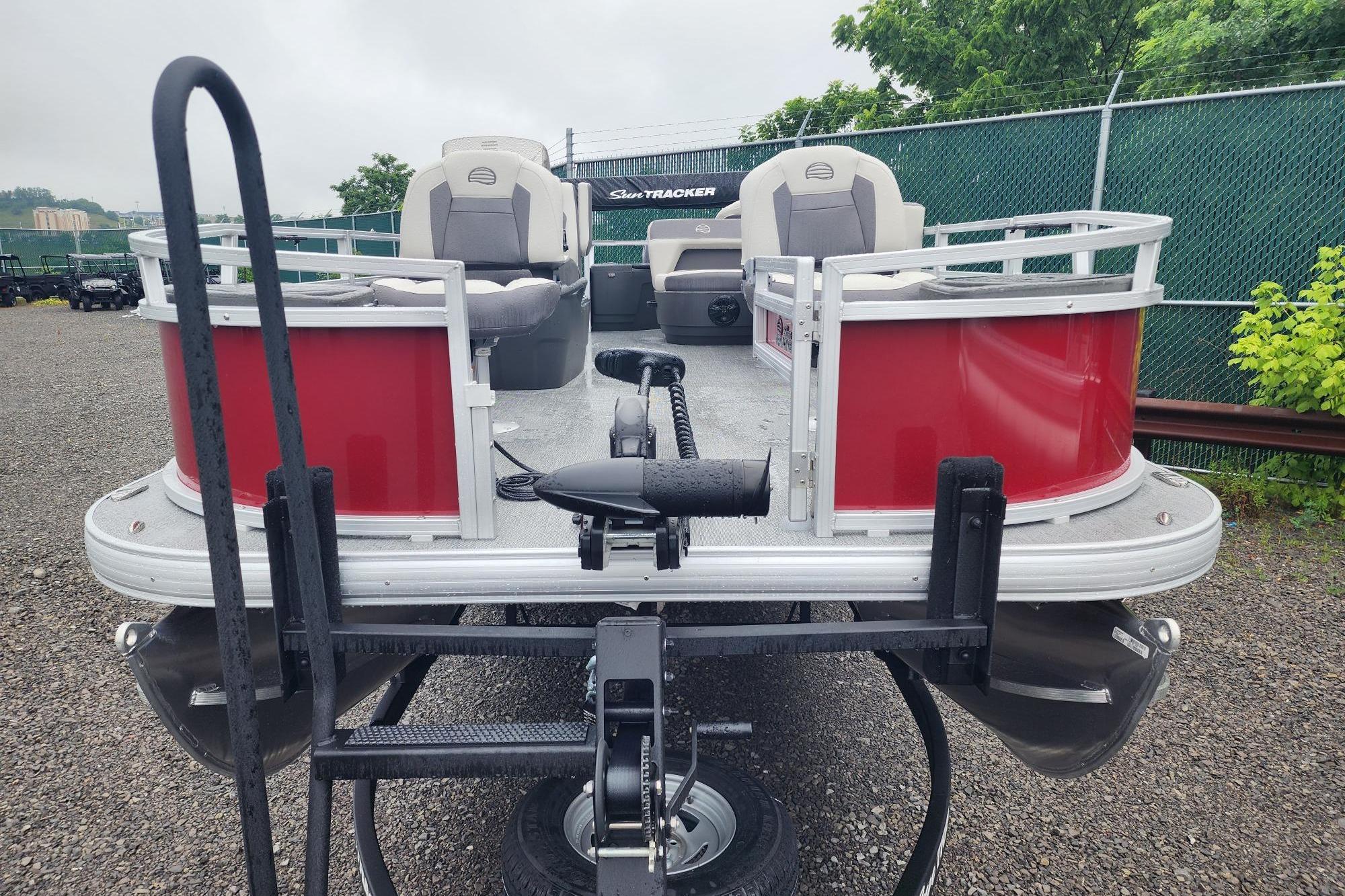 2026 Sun Tracker Bass Buggy 18 DLX pontoon boat with red exterior, parked on gravel.