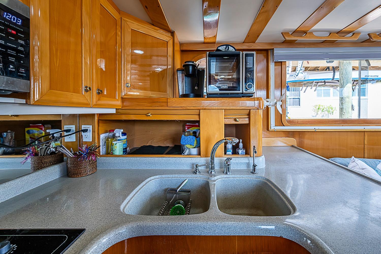 Luxurious kitchen interior of 2003 Magna Marine Nova Scotia 47 yacht, featuring wooden cabinetry and modern appliances.