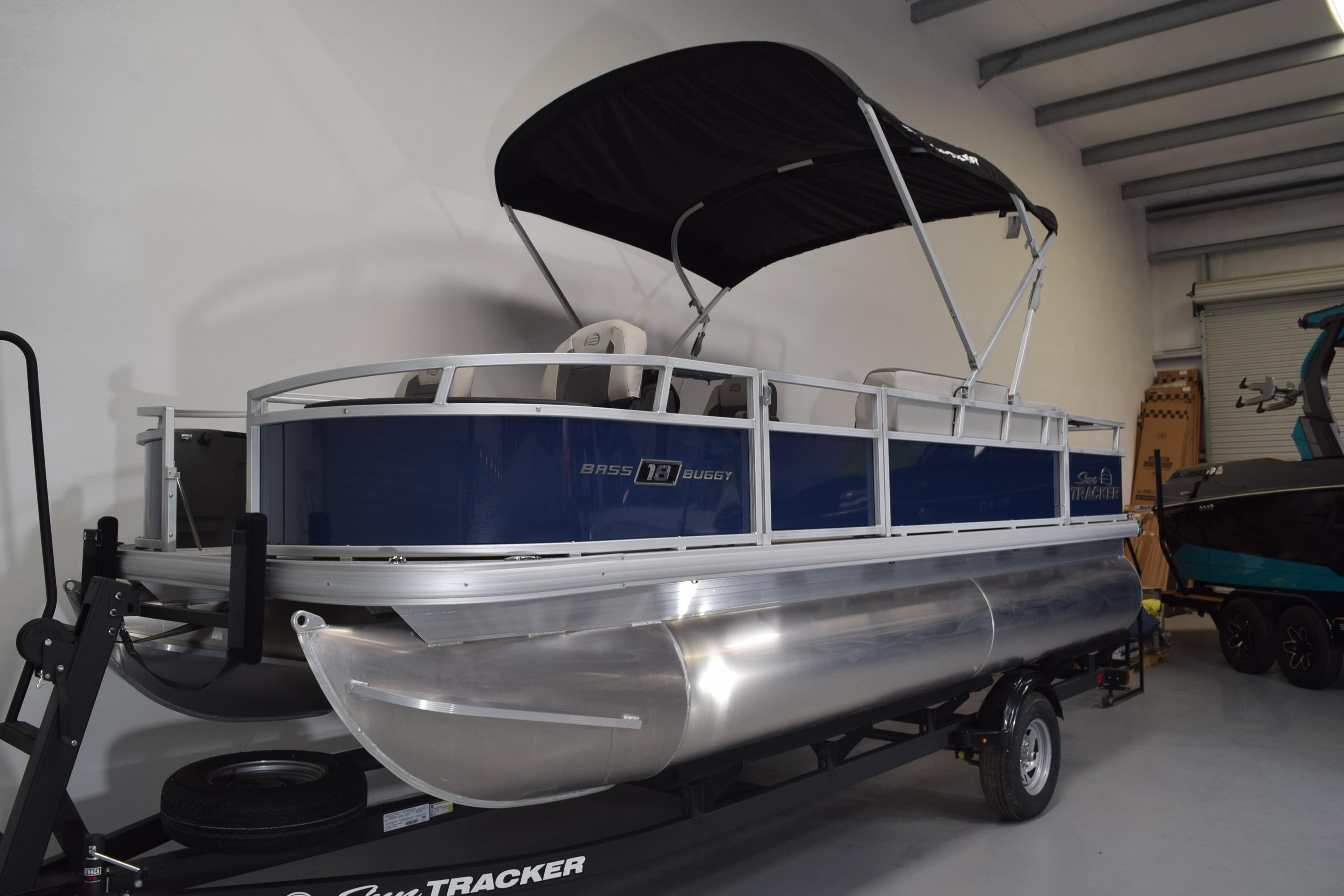2026 Sun Tracker Bass Buggy 18 DLX pontoon boat in showroom, featuring sleek design and canopy.