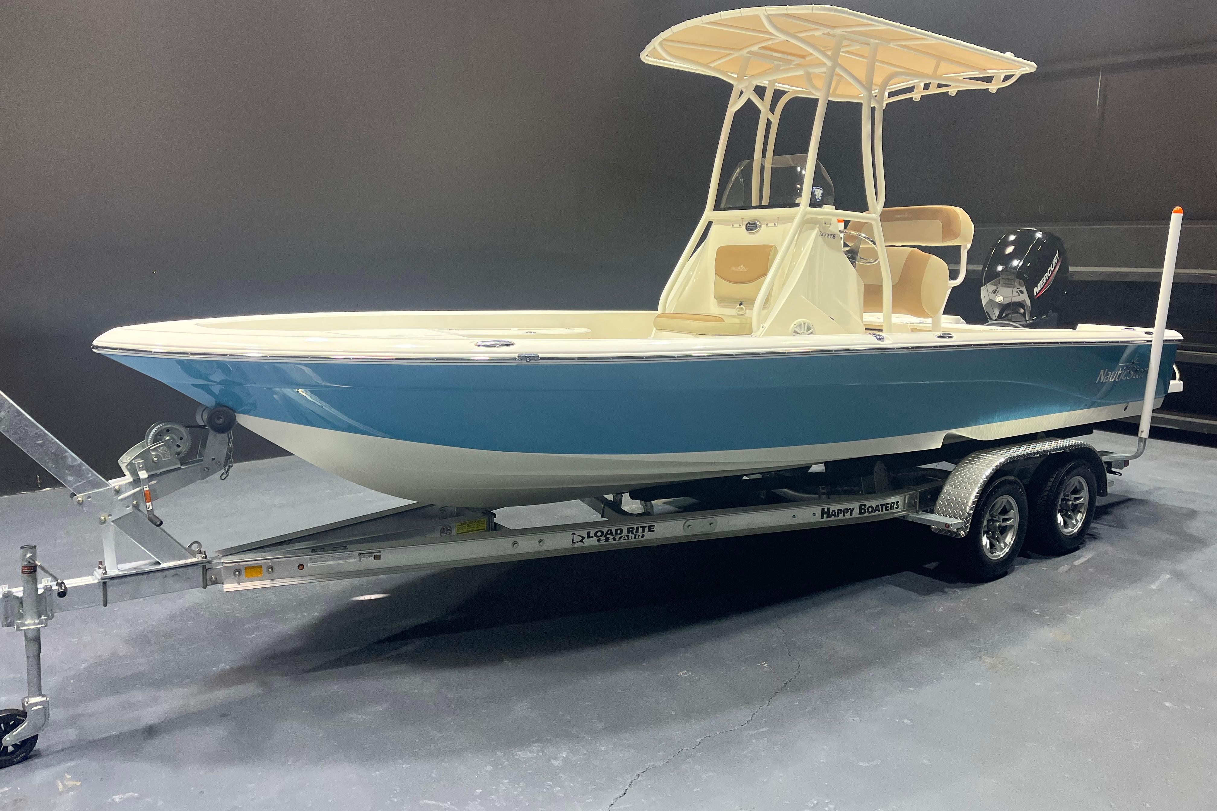 2023 NauticStar 227 XTS boat on trailer, blue hull, indoor display.