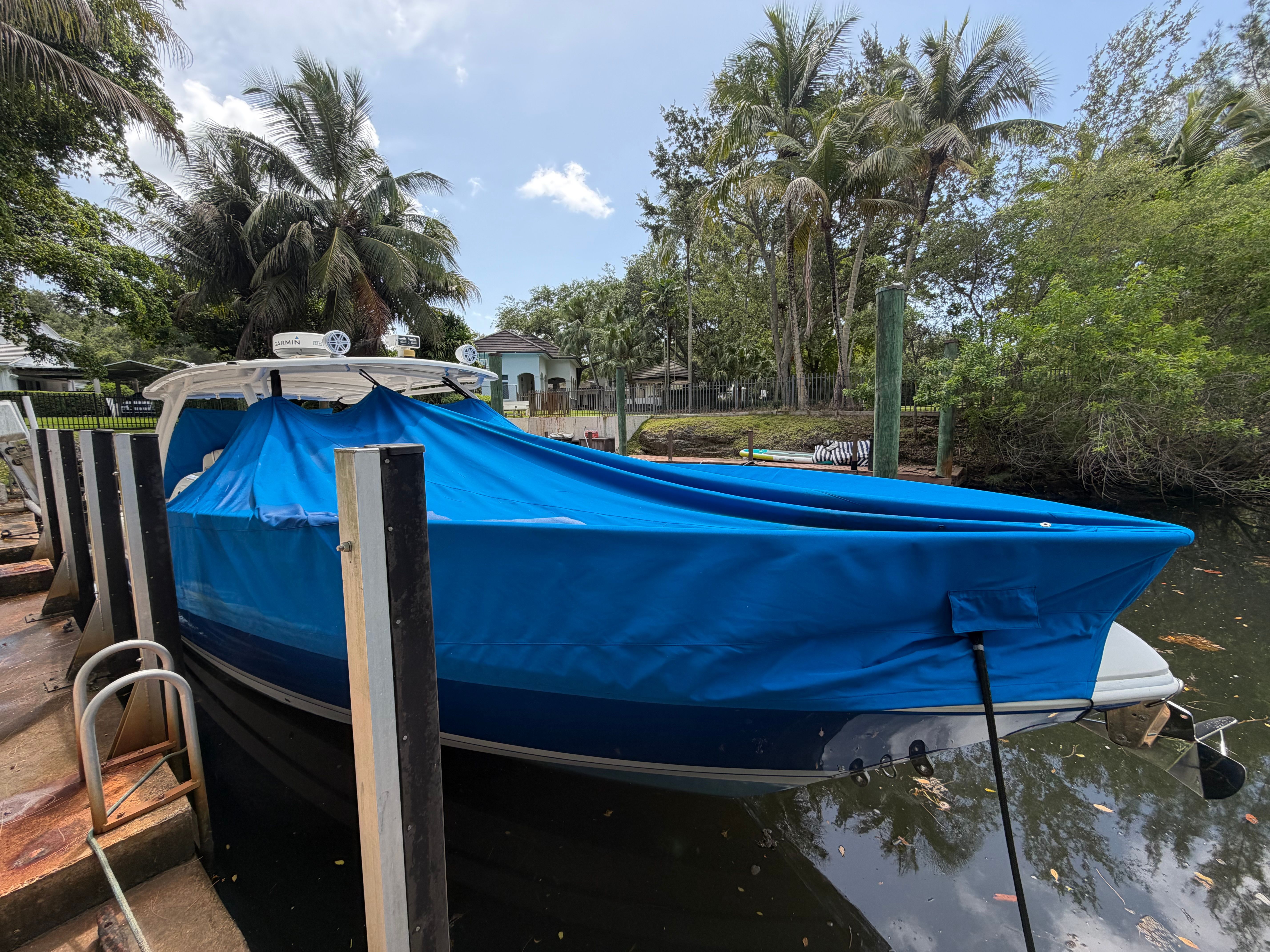 A 2014 Intrepid 375 Walkaround is docked, covered with a blue tarp.
