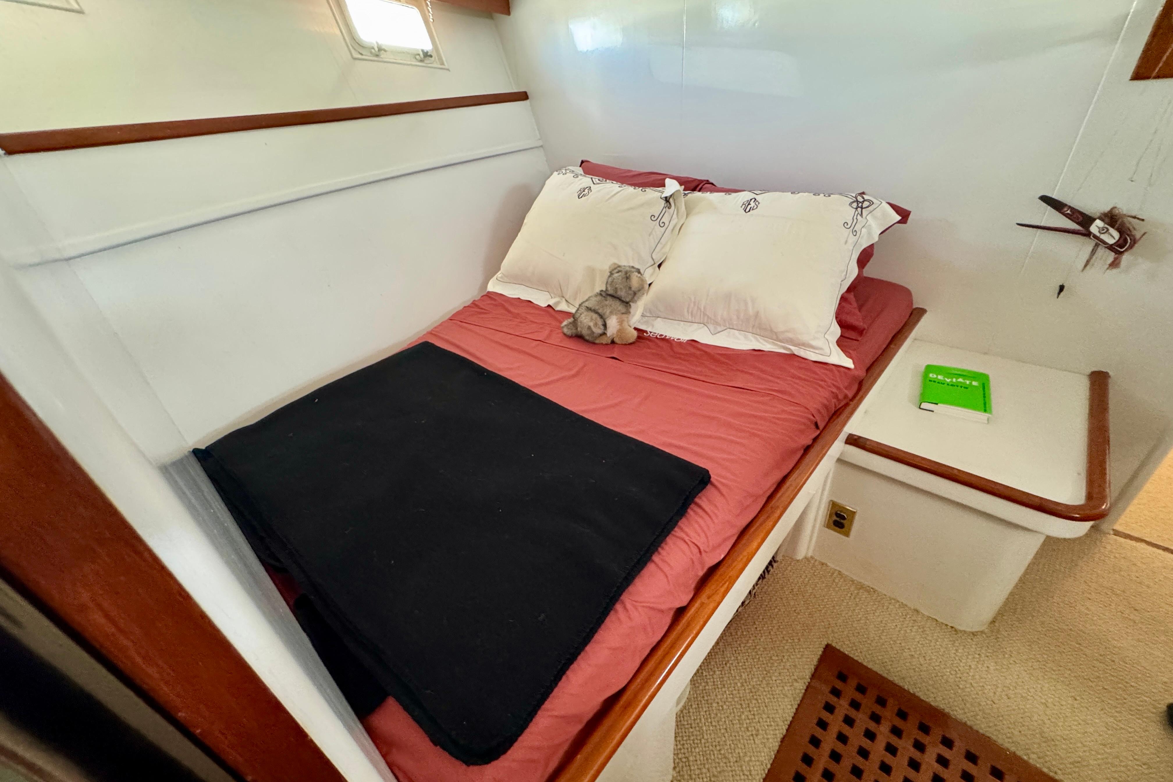 Cozy cabin interior of a 1958 Blanchard Pilothouse boat with a neatly made bed.