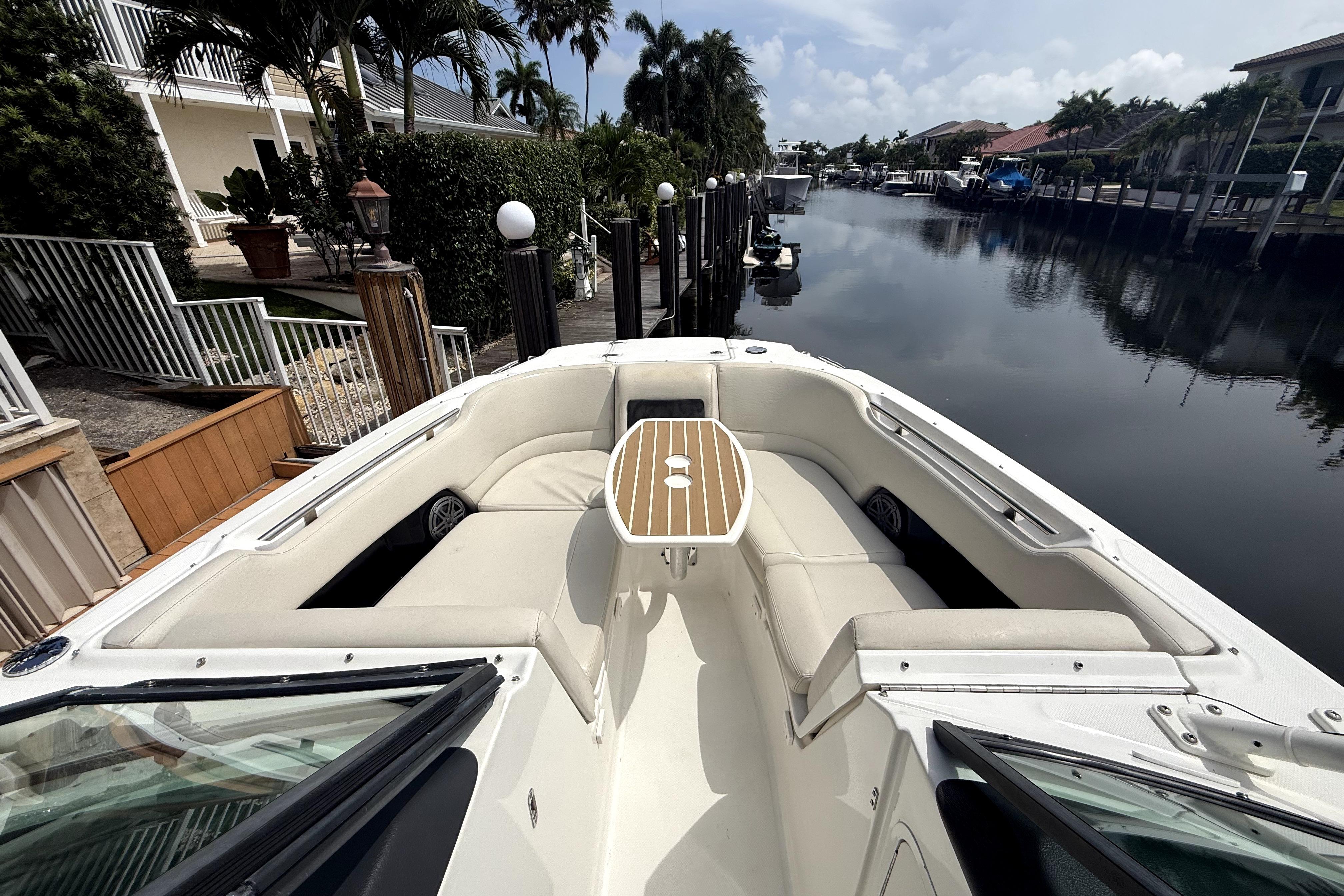 2018 Boston Whaler 230 Vantage boat docked by a serene canal with lush surroundings.
