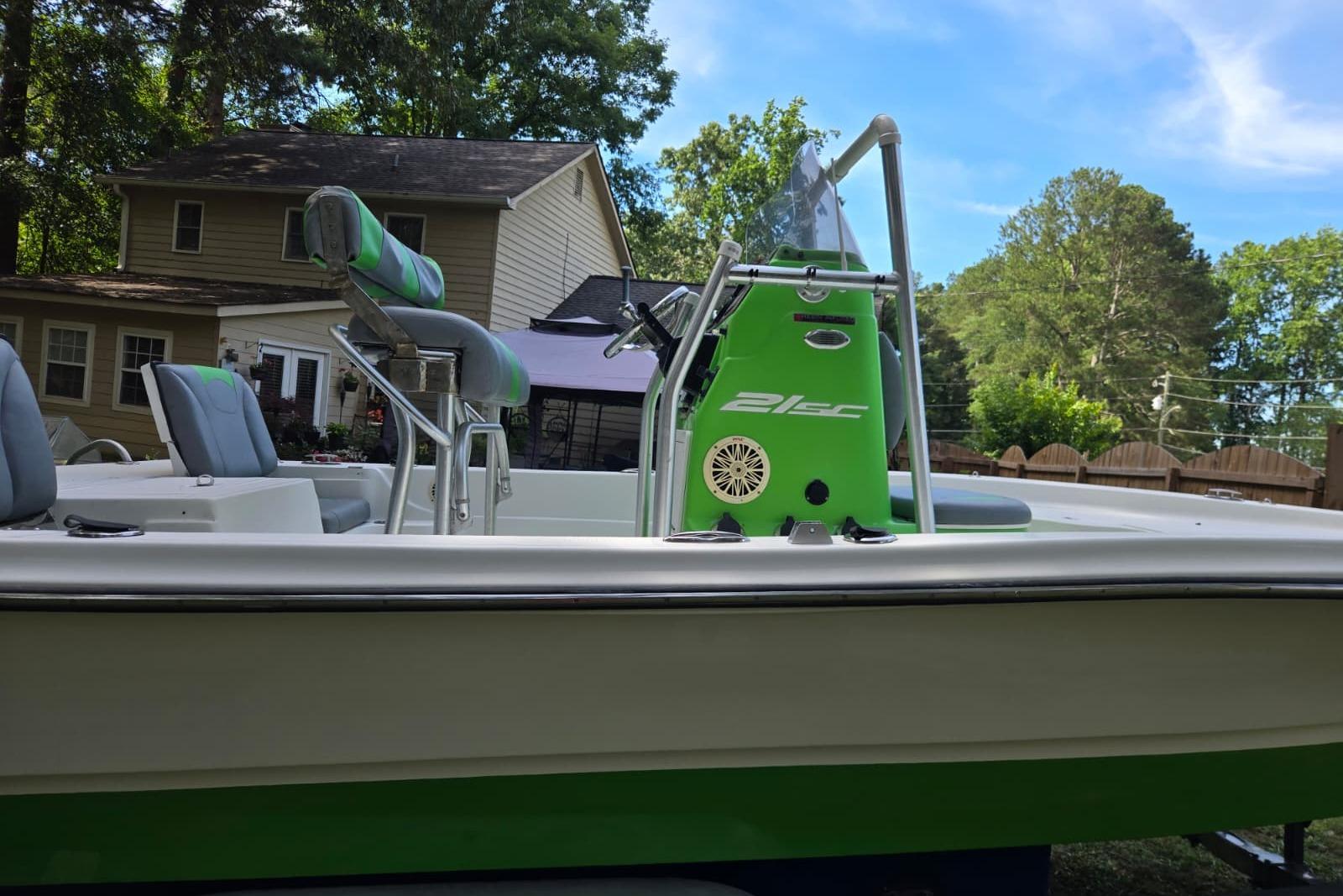 2016 Epic 21 Sport Console boat with green accents, parked near a house.