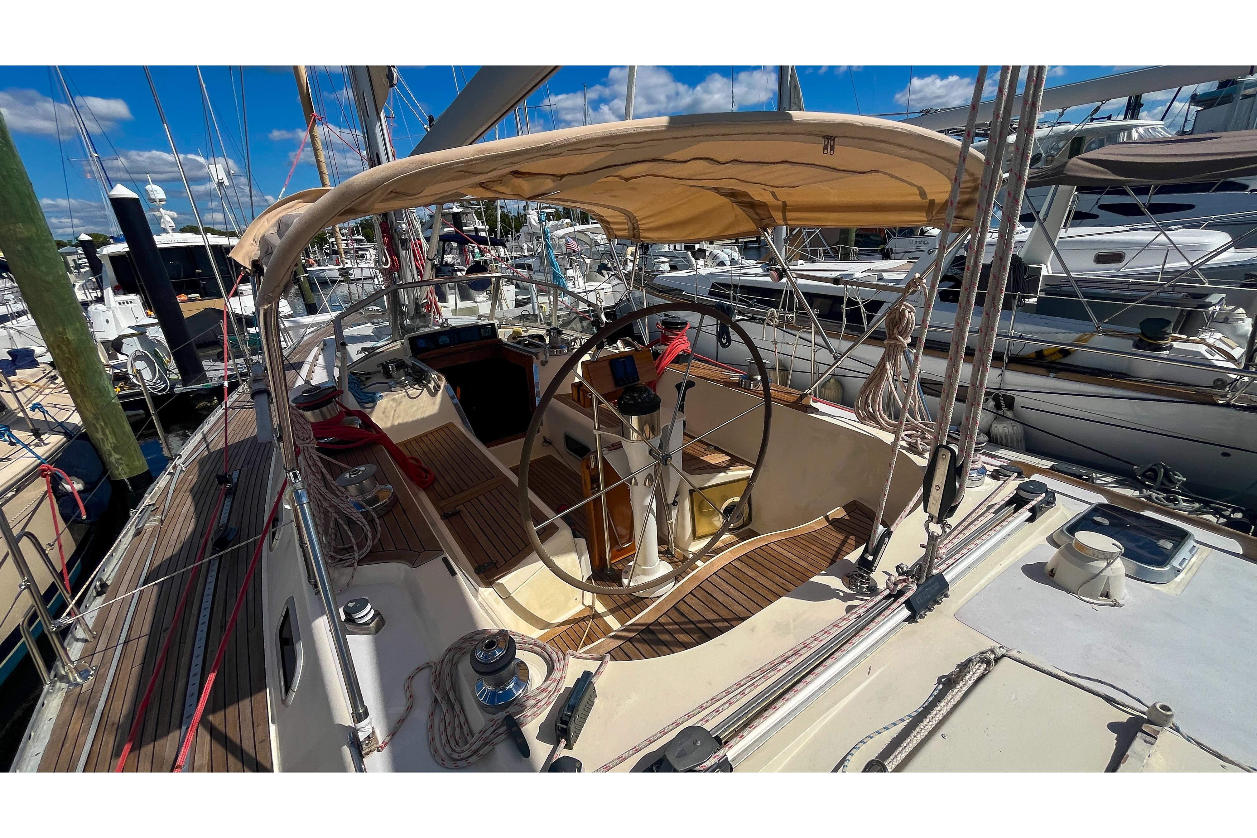 1991 Oyster LW48 sailboat cockpit with wooden deck and steering wheel at marina.