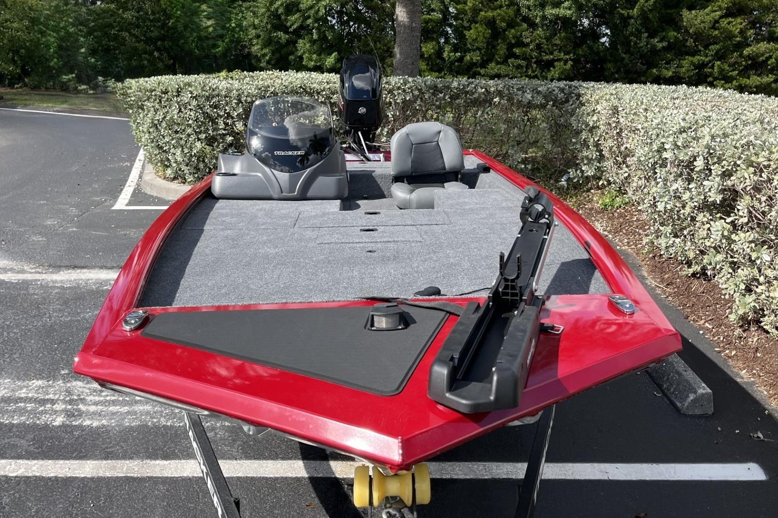 2026 Tracker Pro 170 boat with red exterior, parked in a lot, surrounded by greenery.