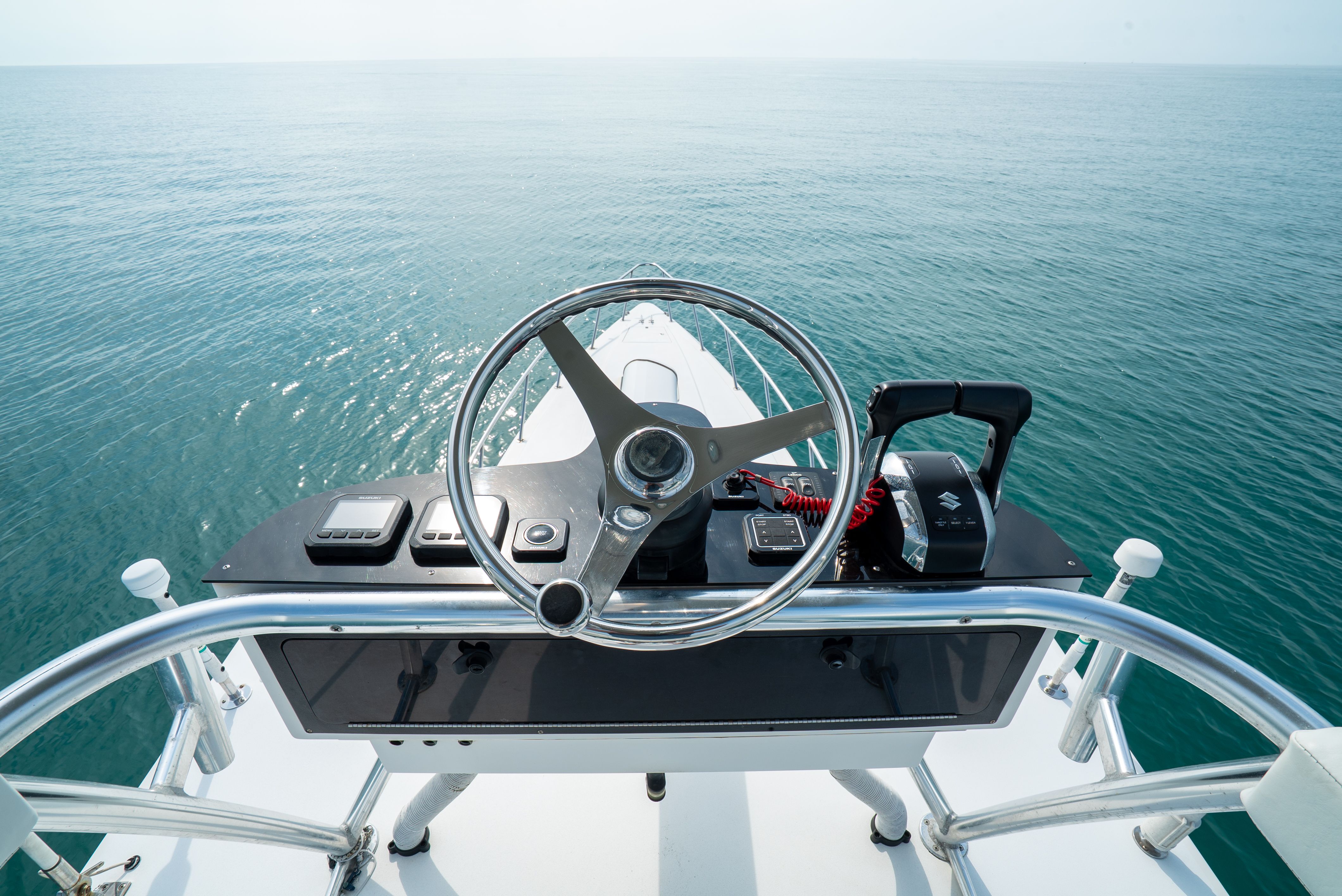 The image shows a boat's helm overlooking the open sea.