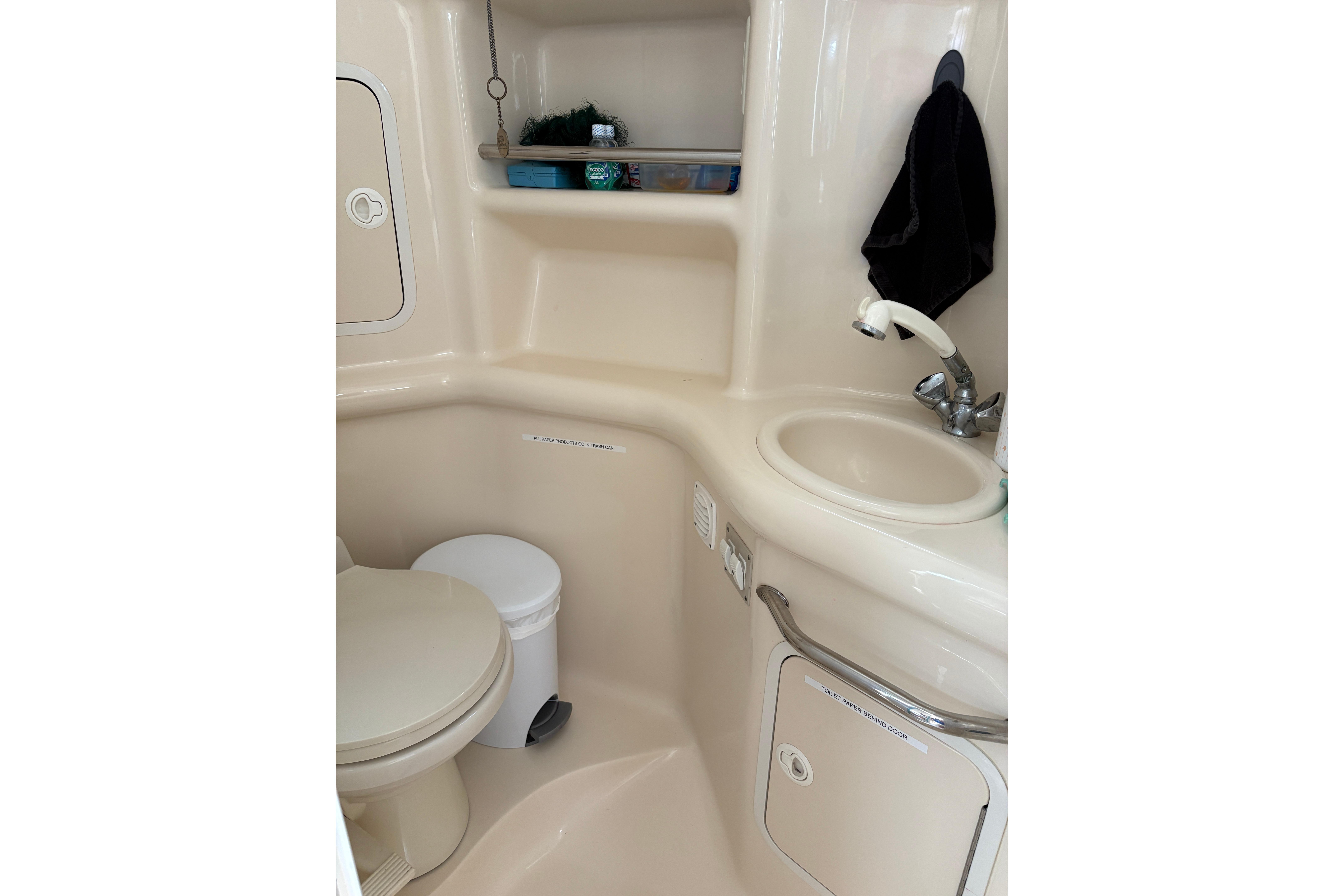 2001 Sea Ray Sundancer 310 bathroom with sink, toilet, and storage shelves.