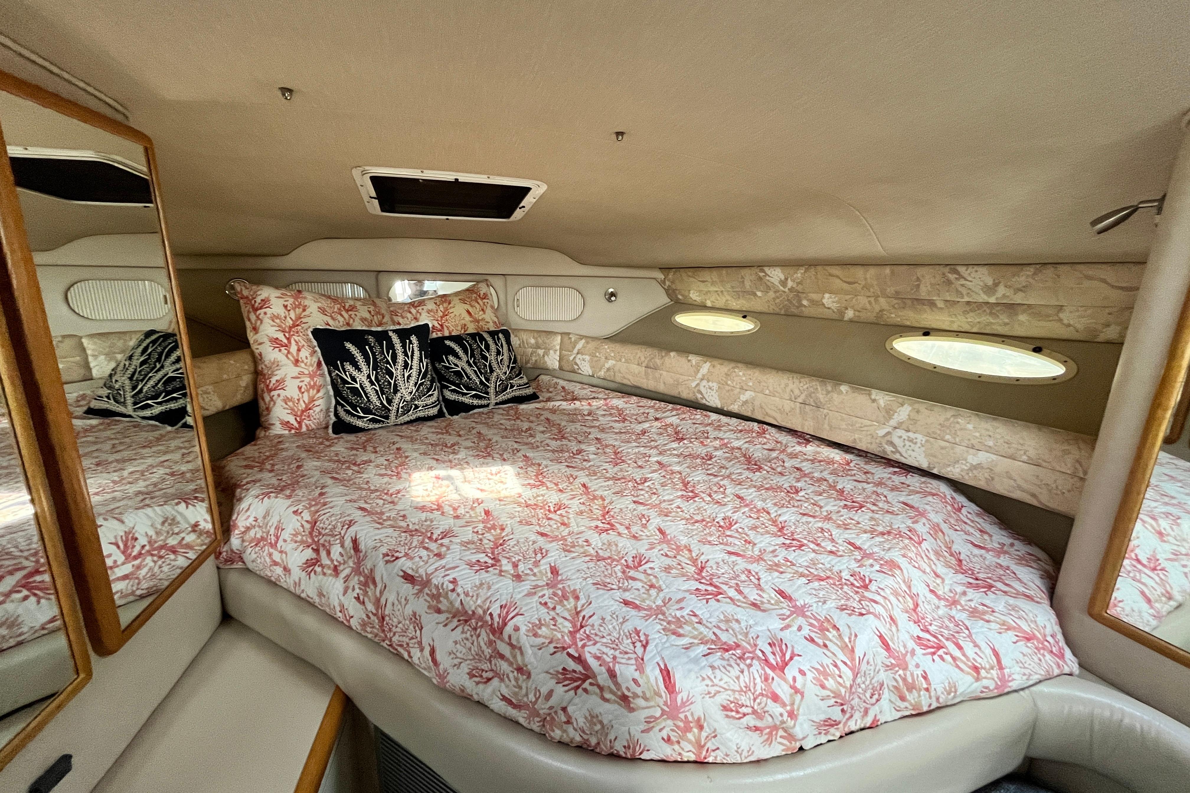Interior cabin of a 1995 Sea Ray Sundancer 330 with coral-themed bedding.