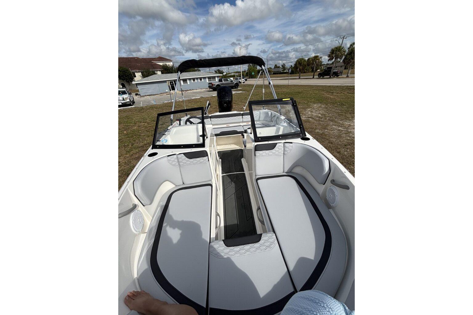 2025 Bayliner Element M17 boat interior with seating and open windshield under a cloudy sky.