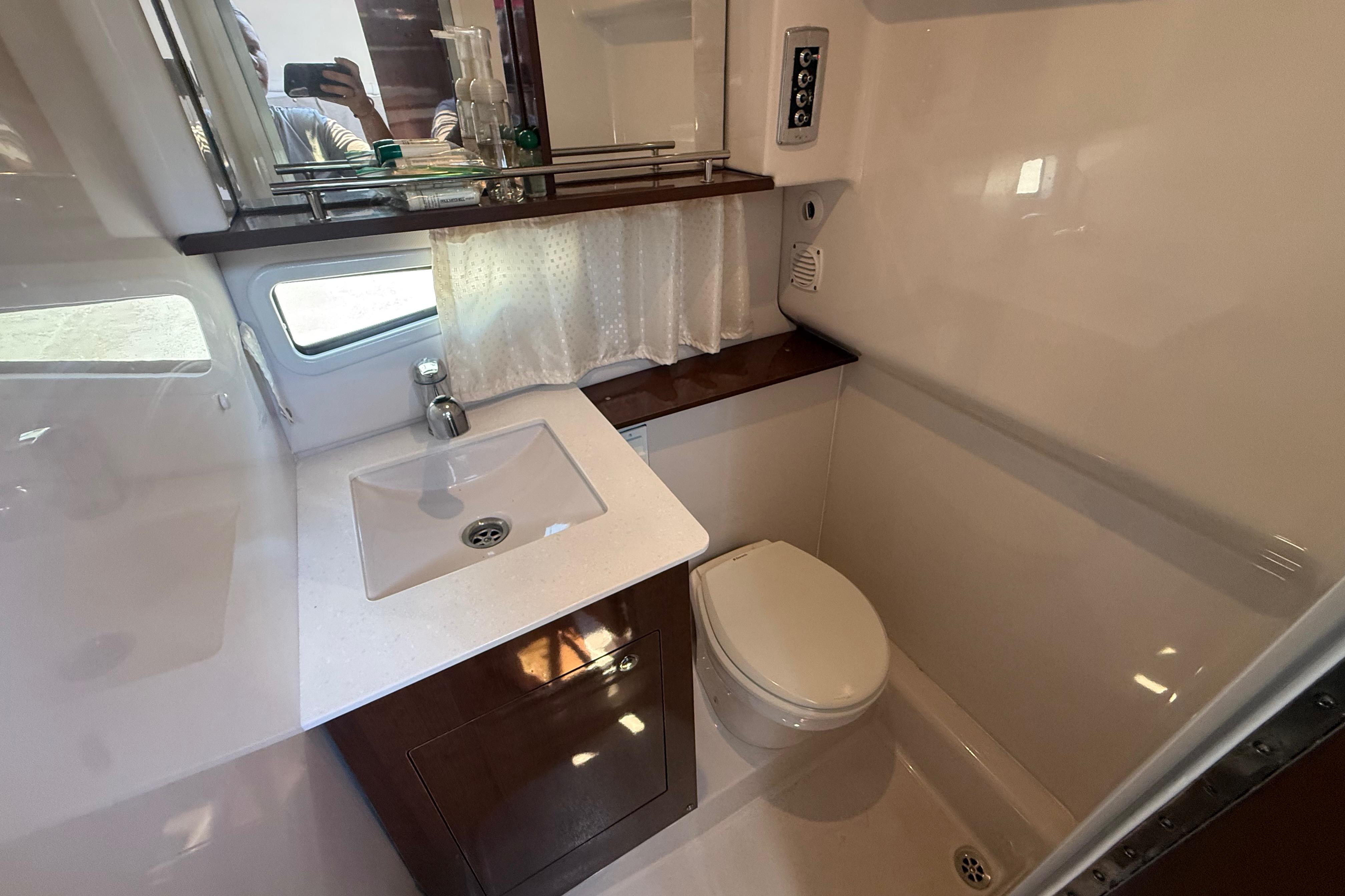2017 Four Winns V275 boat bathroom with sink, toilet, and window.