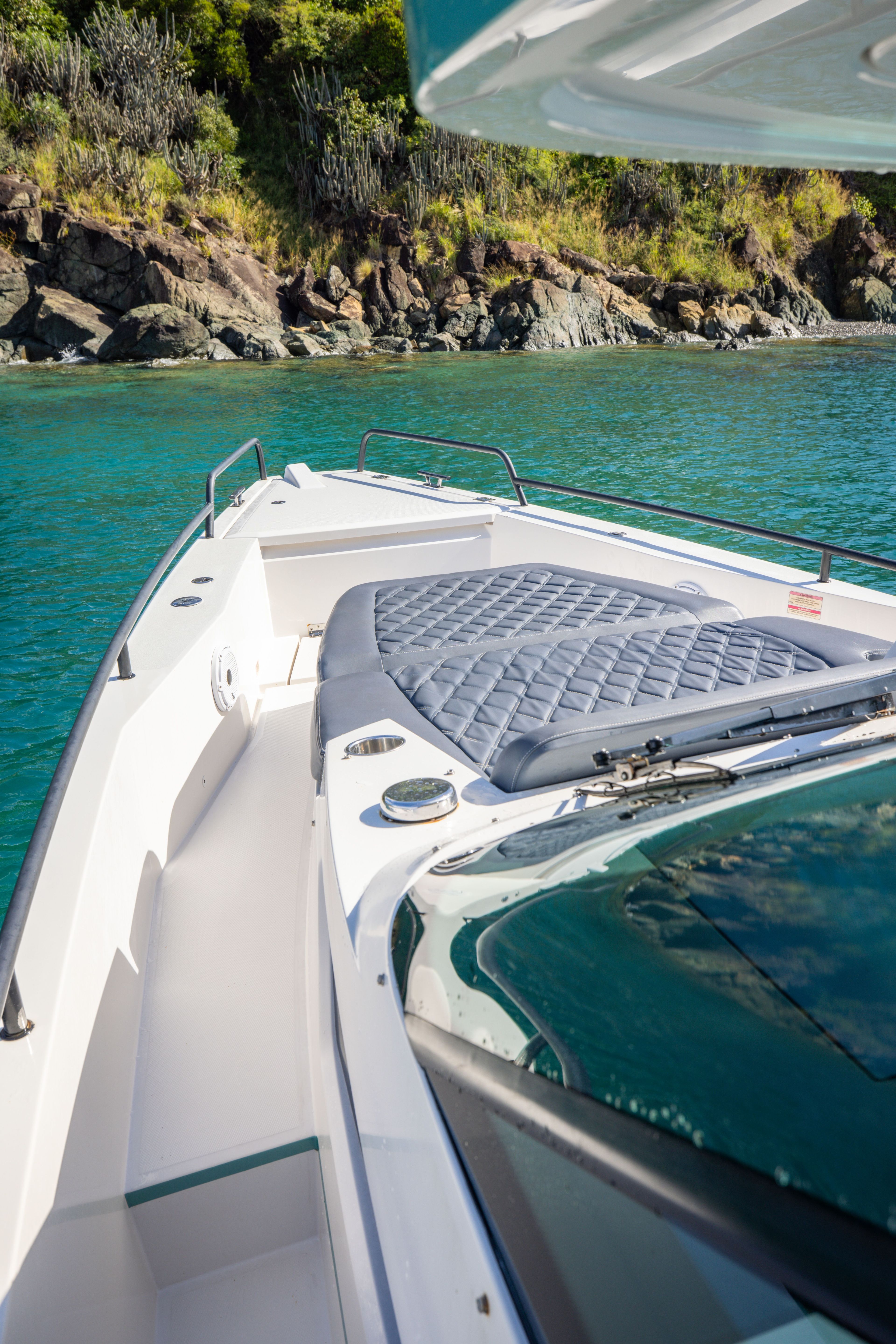 A 2020 Axopar 37 SUN TOP is in clear water near a rocky shoreline.