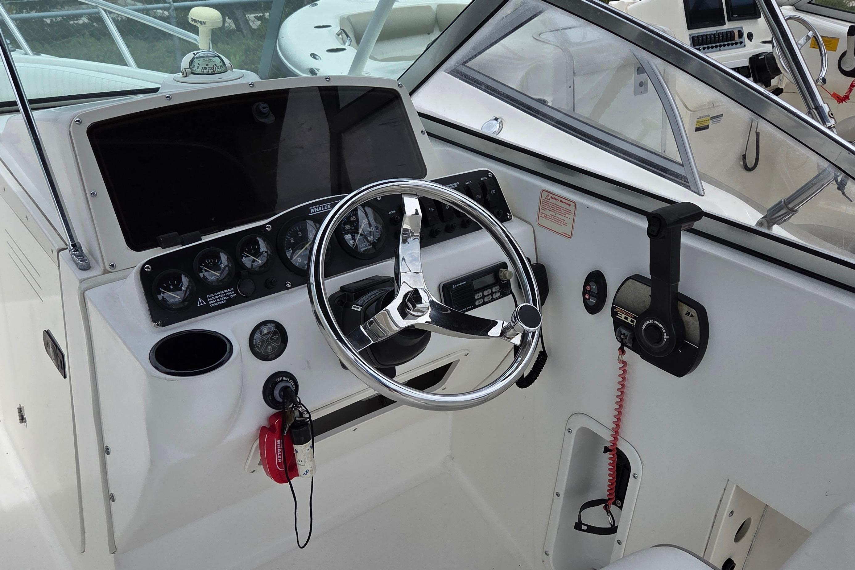 Cockpit of a 2000 Boston Whaler 21 Ventura boat, featuring steering wheel and control panel.