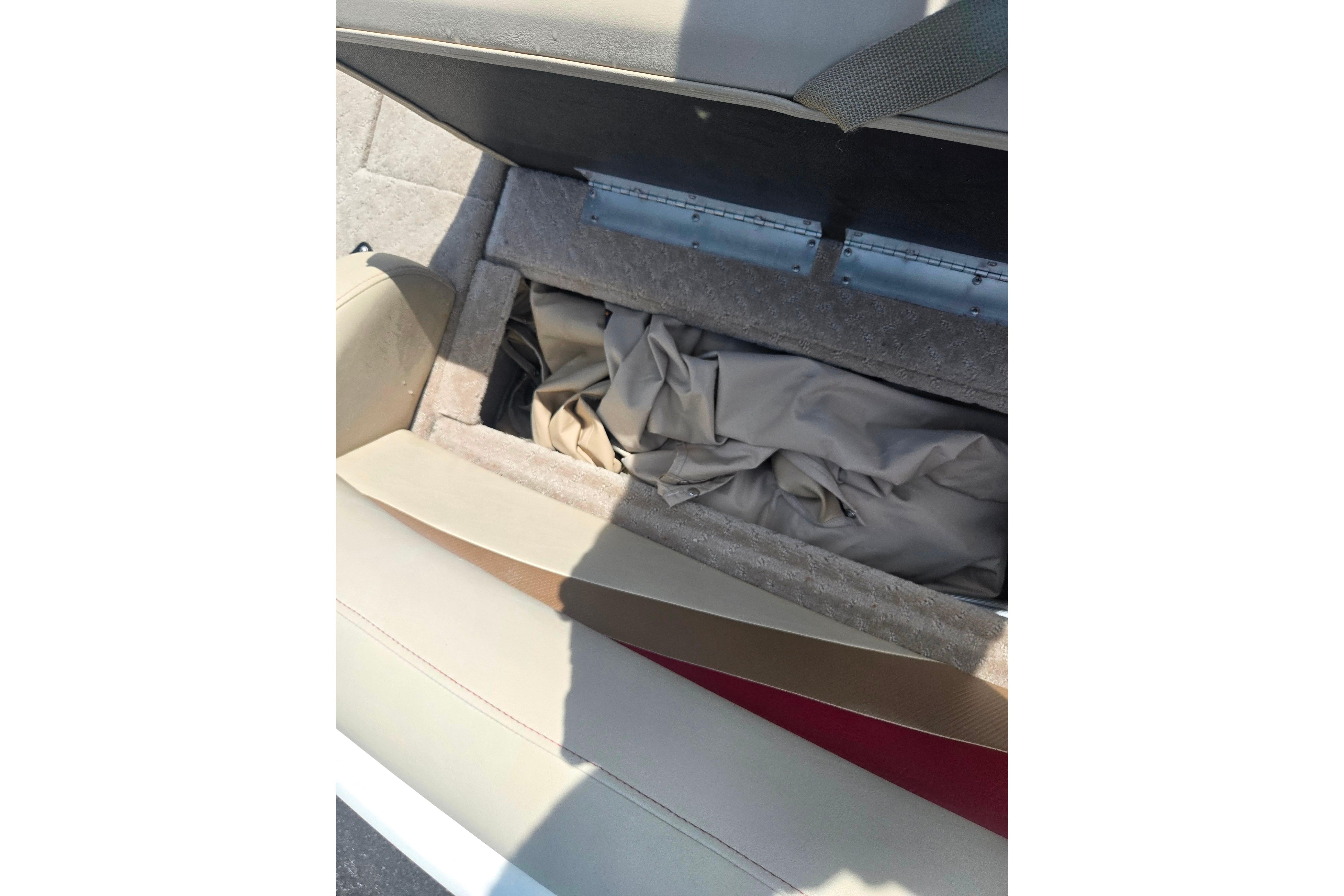 Open storage compartment on a 2015 Lowe Sport Deck 224 boat, containing fabric.