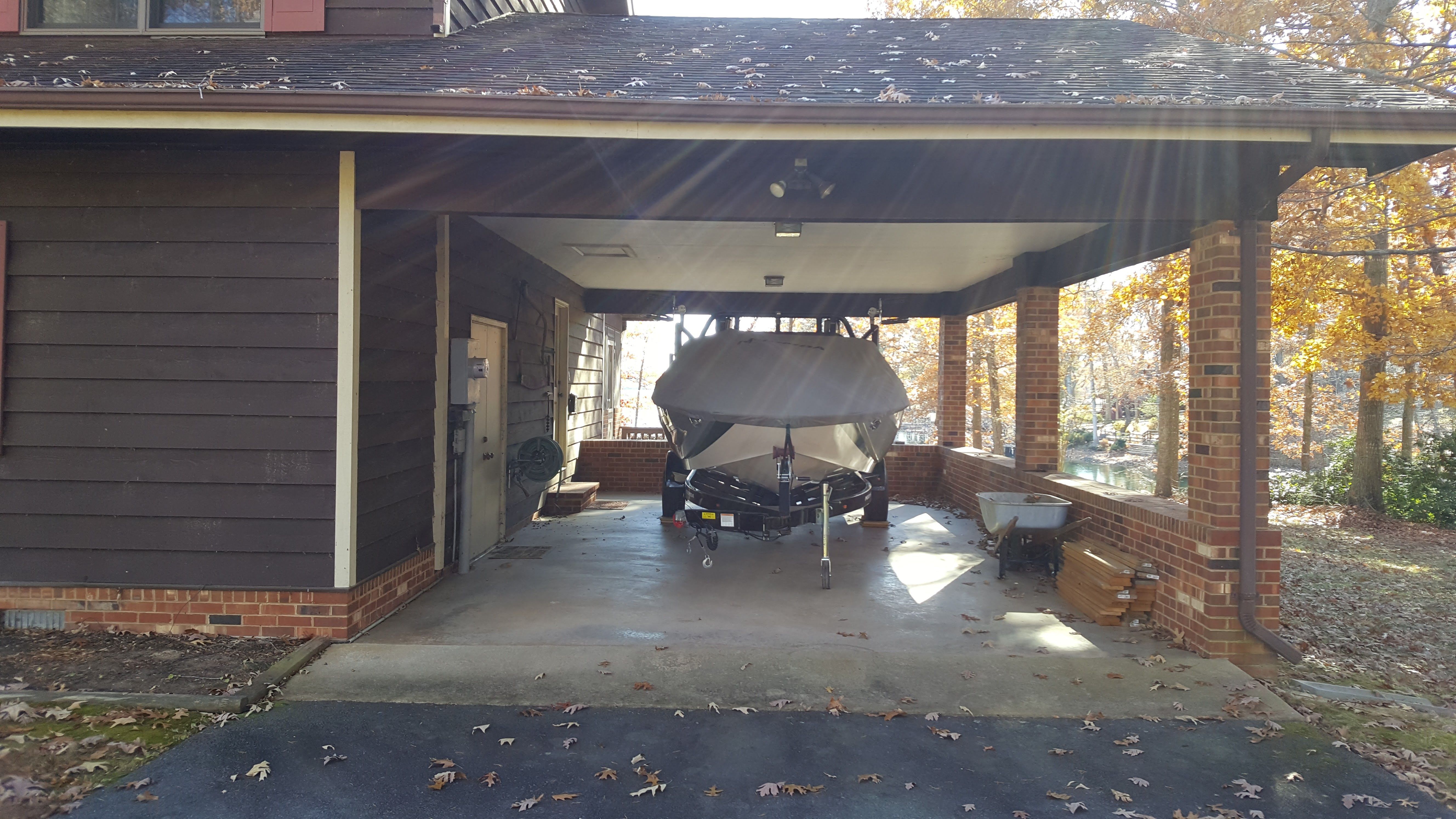 A 2016 Moomba Mondo boat is parked under a carport next to a house.
