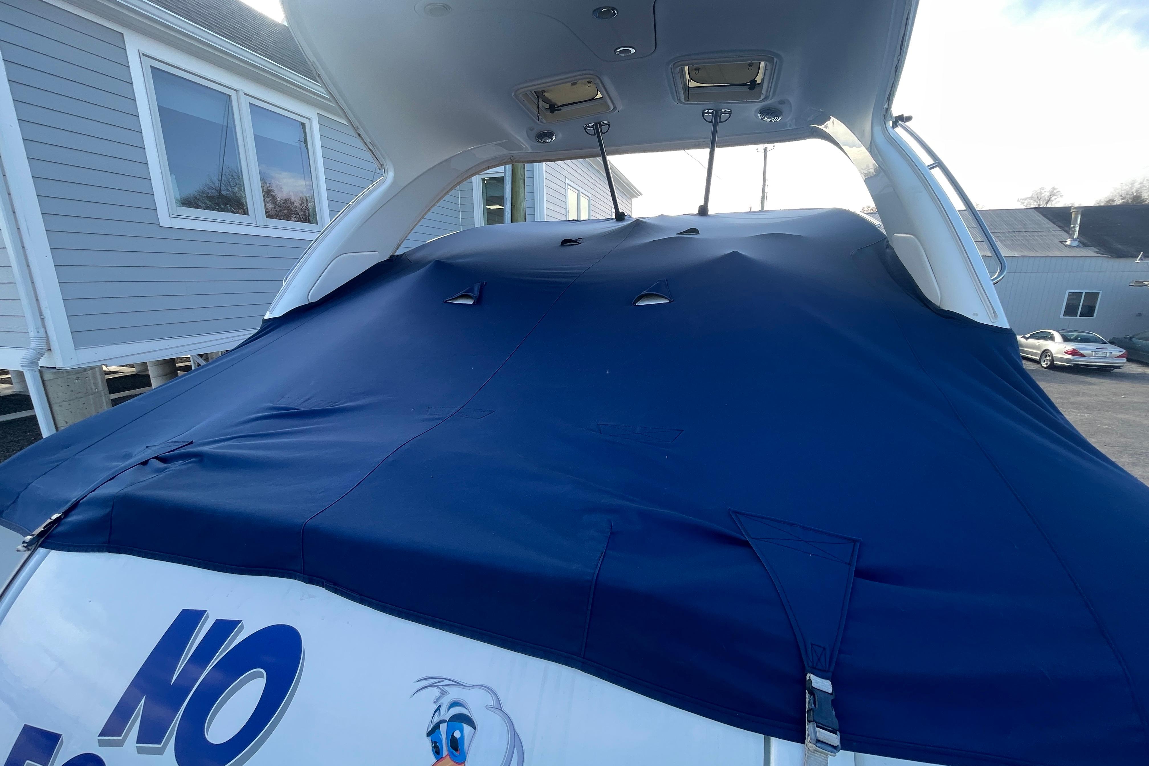 2011 Formula 34 Performance Cruiser with blue cover, docked near residential buildings.
