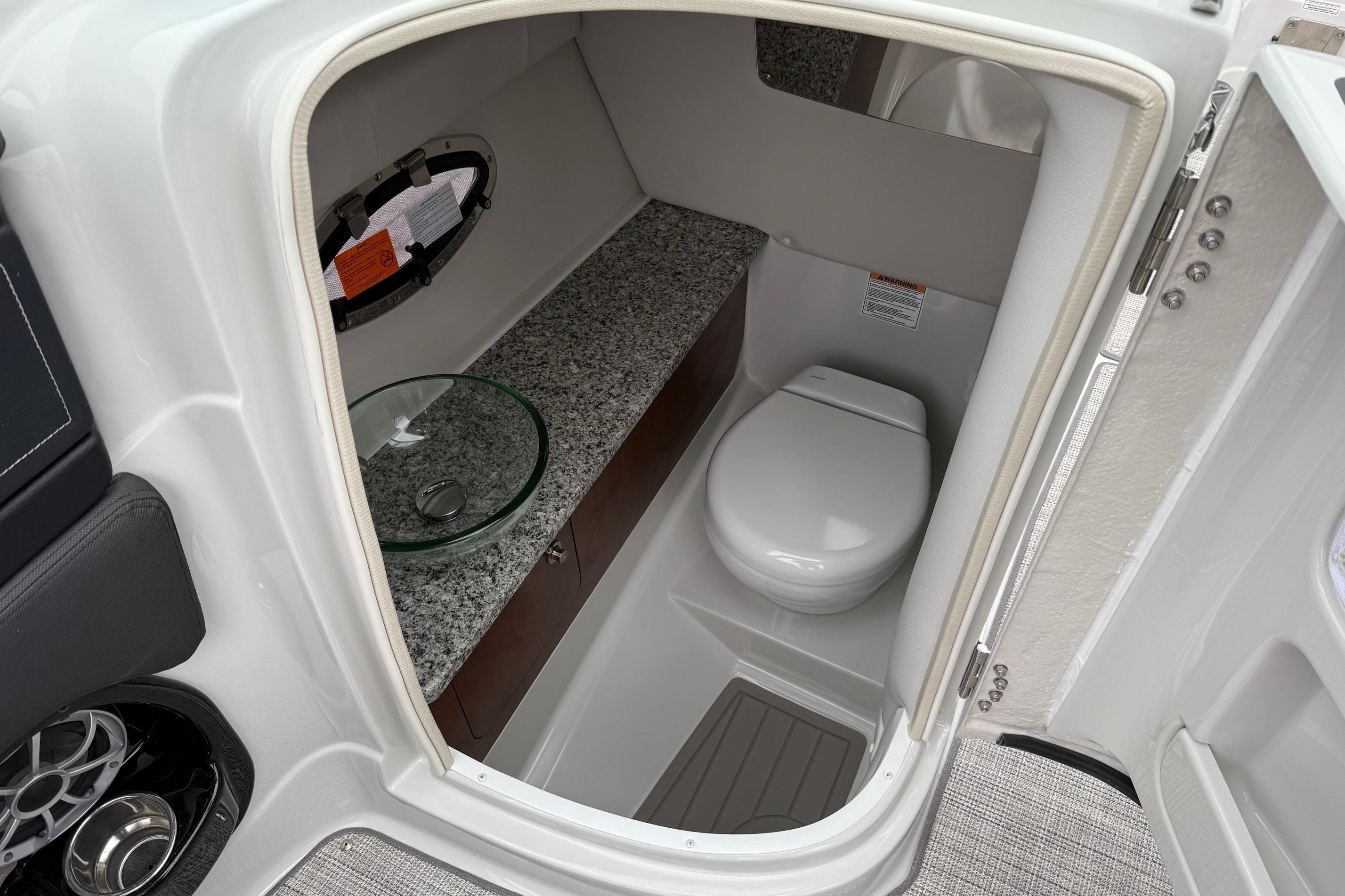 2026 Crownline 288 SS boat interior with modern bathroom, featuring granite countertop and compact toilet.