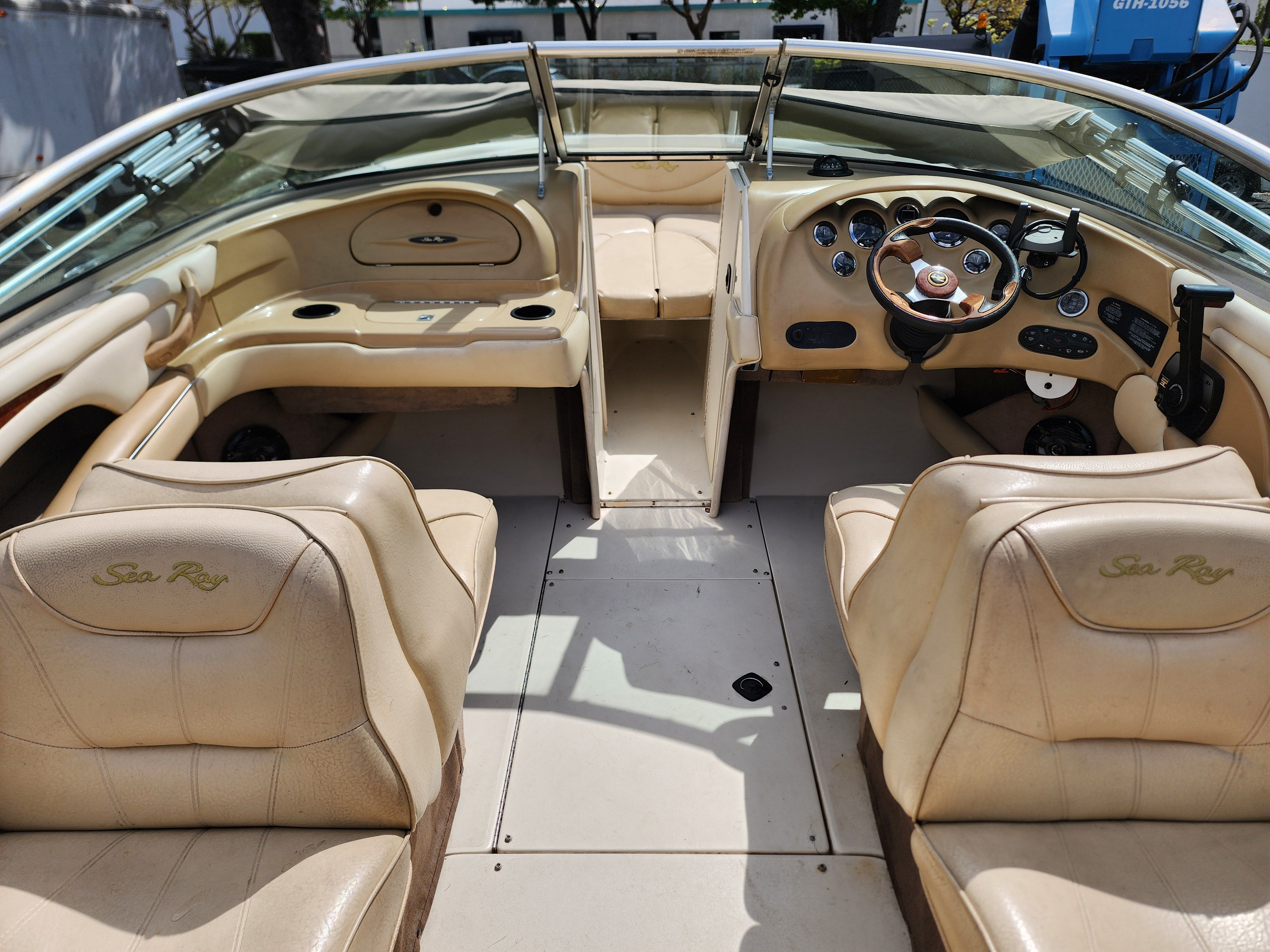 Interior view of a 1999 Sea Ray 210 Bowrider Signature with beige leather seats and steering console.