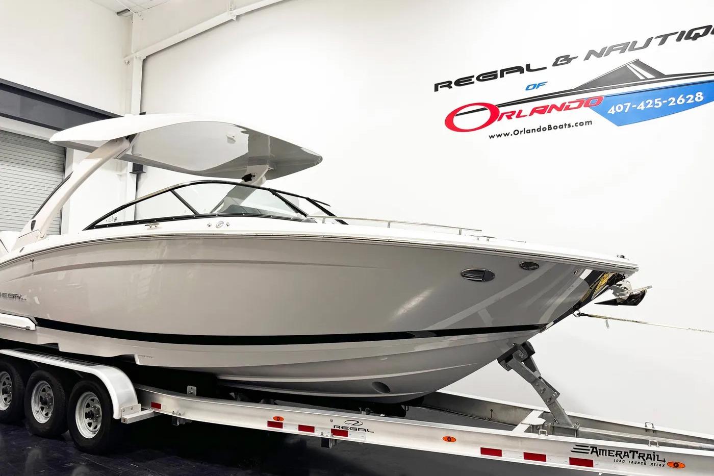 2026 Regal LX9 boat on trailer in showroom, Orlando Boats signage visible.
