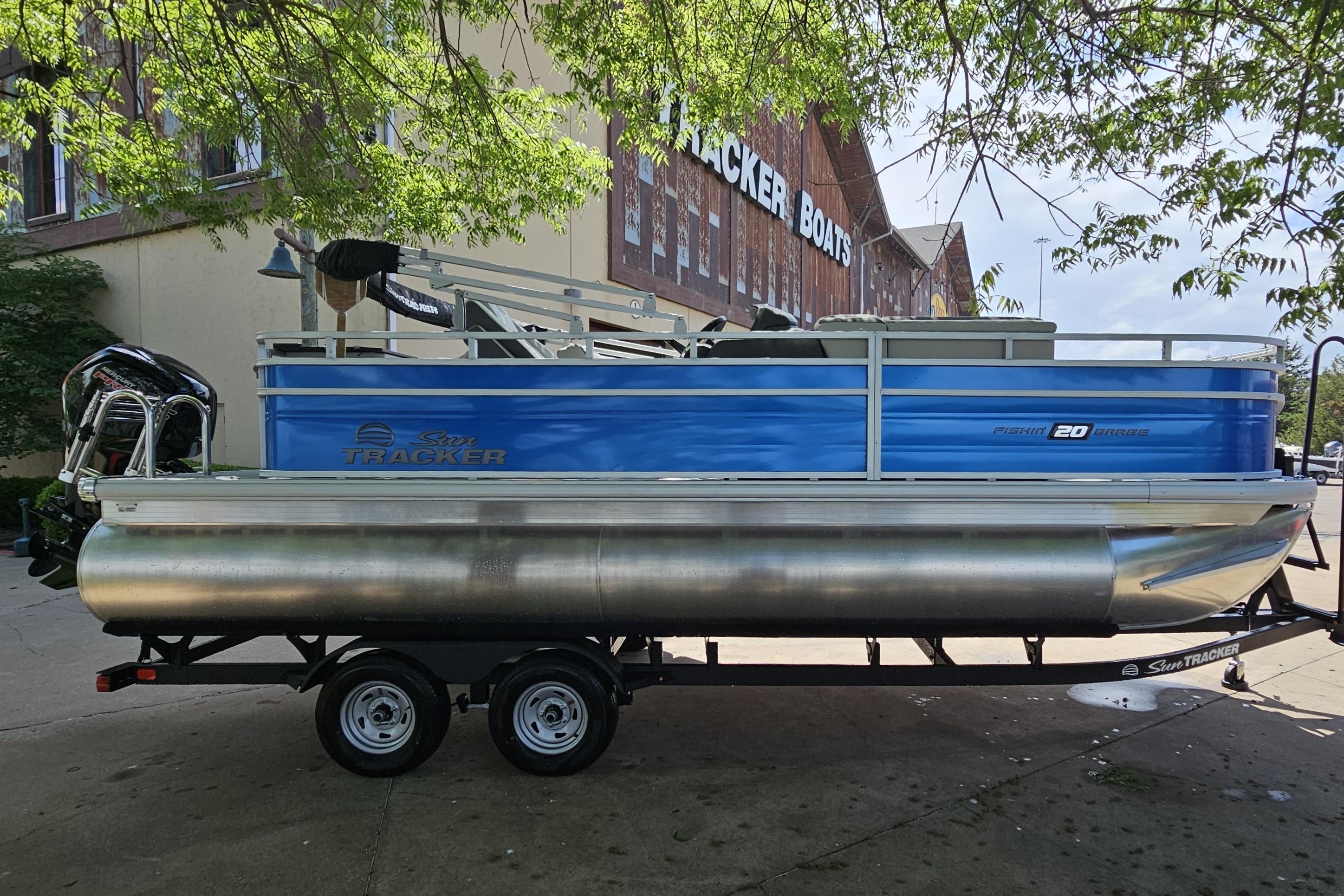 2026 Sun Tracker Fishin' Barge 20 DLX pontoon boat on trailer, parked outdoors.