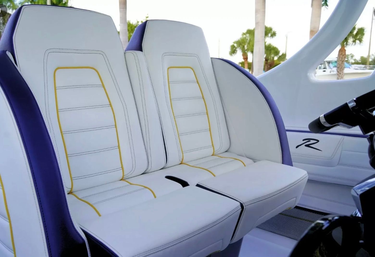 Two luxurious white seats with yellow stitching in a modern boat.
