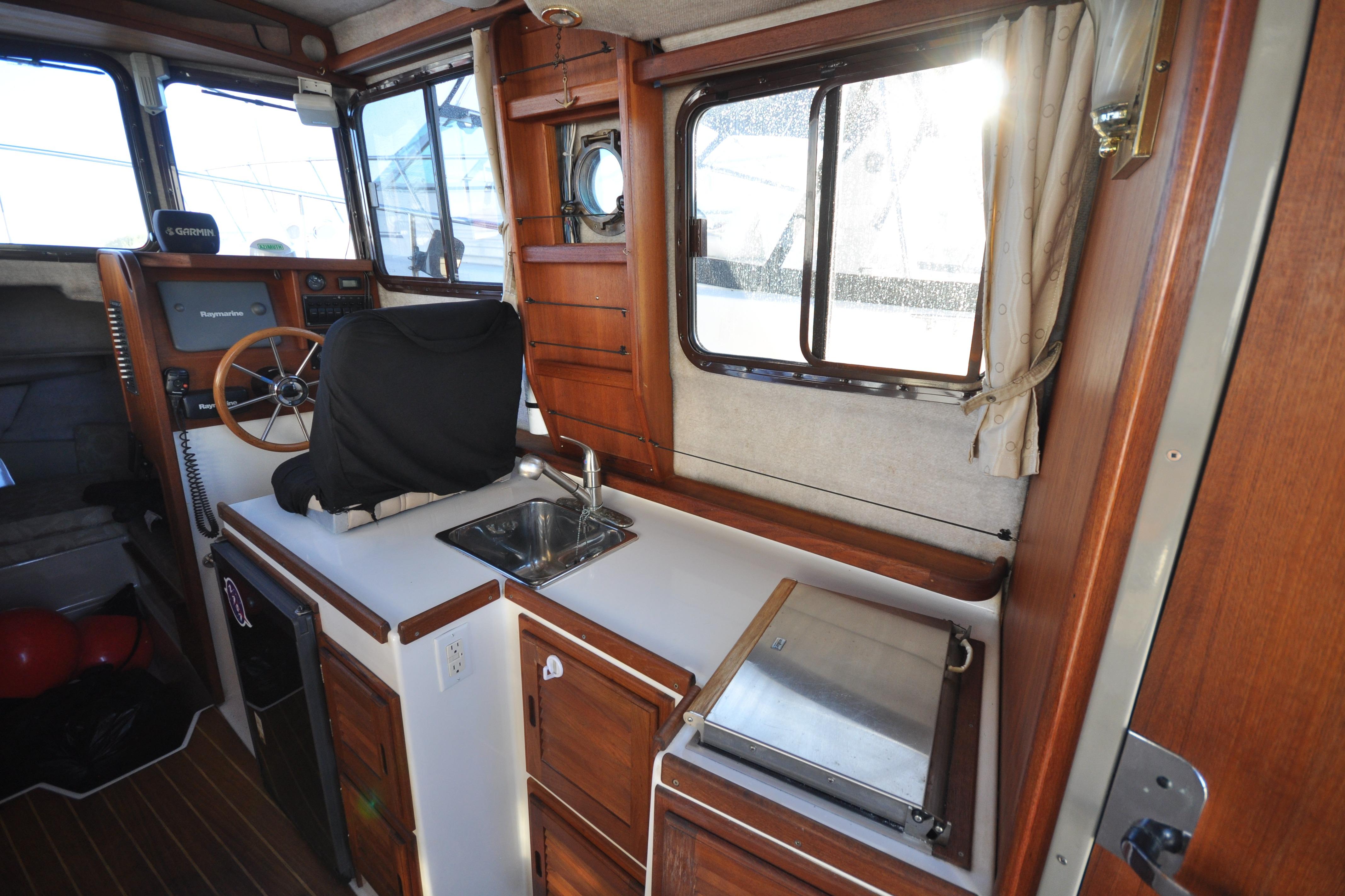 Interior of 2007 Ranger Tug R-25 boat with helm, sink, and wooden cabinetry.