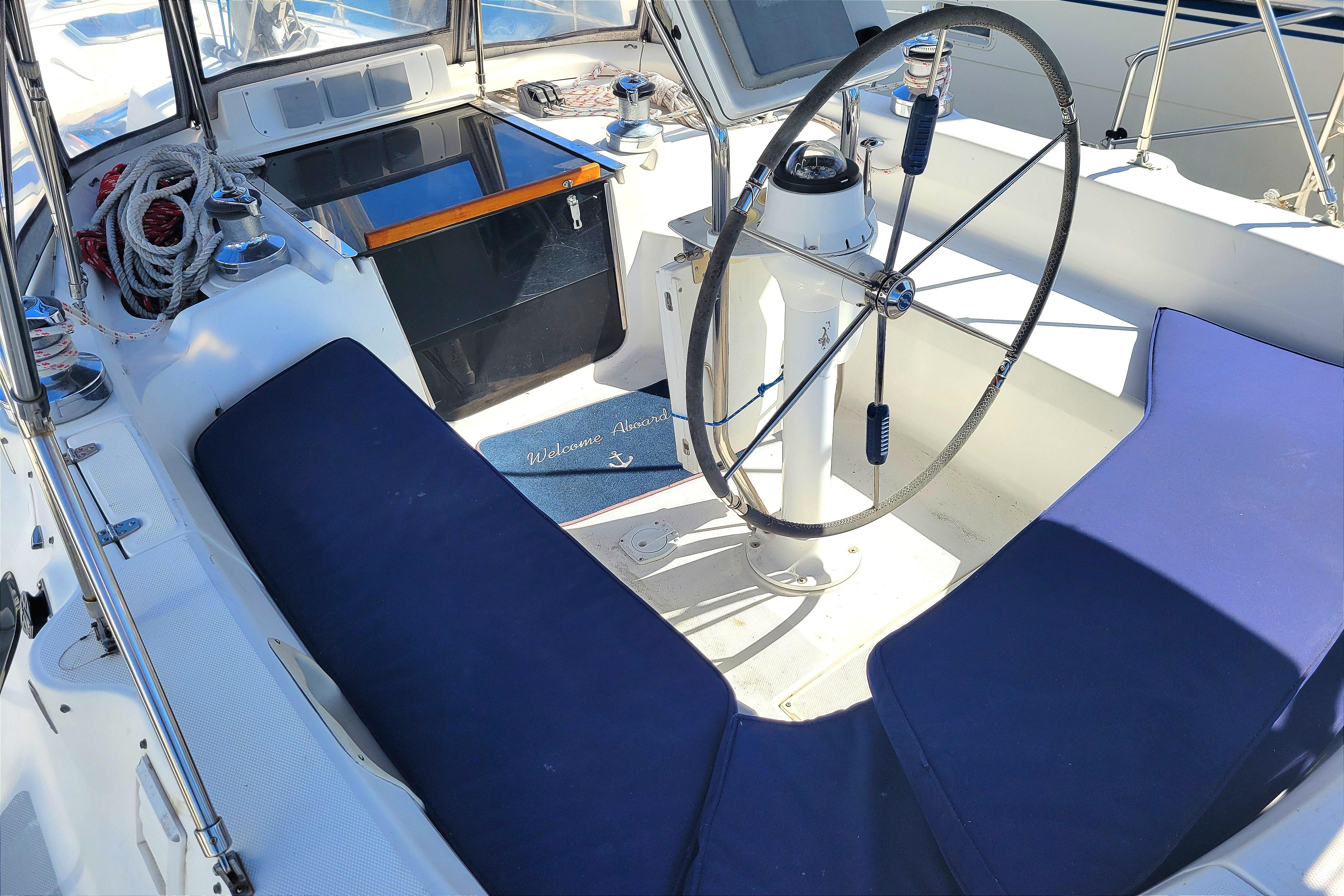 Cockpit of 2001 Hunter Passage 420 sailboat with steering wheel and blue seating.