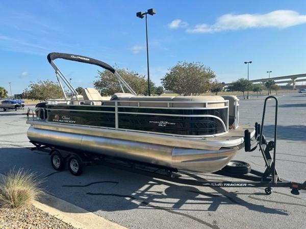 2024 Sun Tracker SportFish 22 DLX pontoon boat on trailer in parking lot.