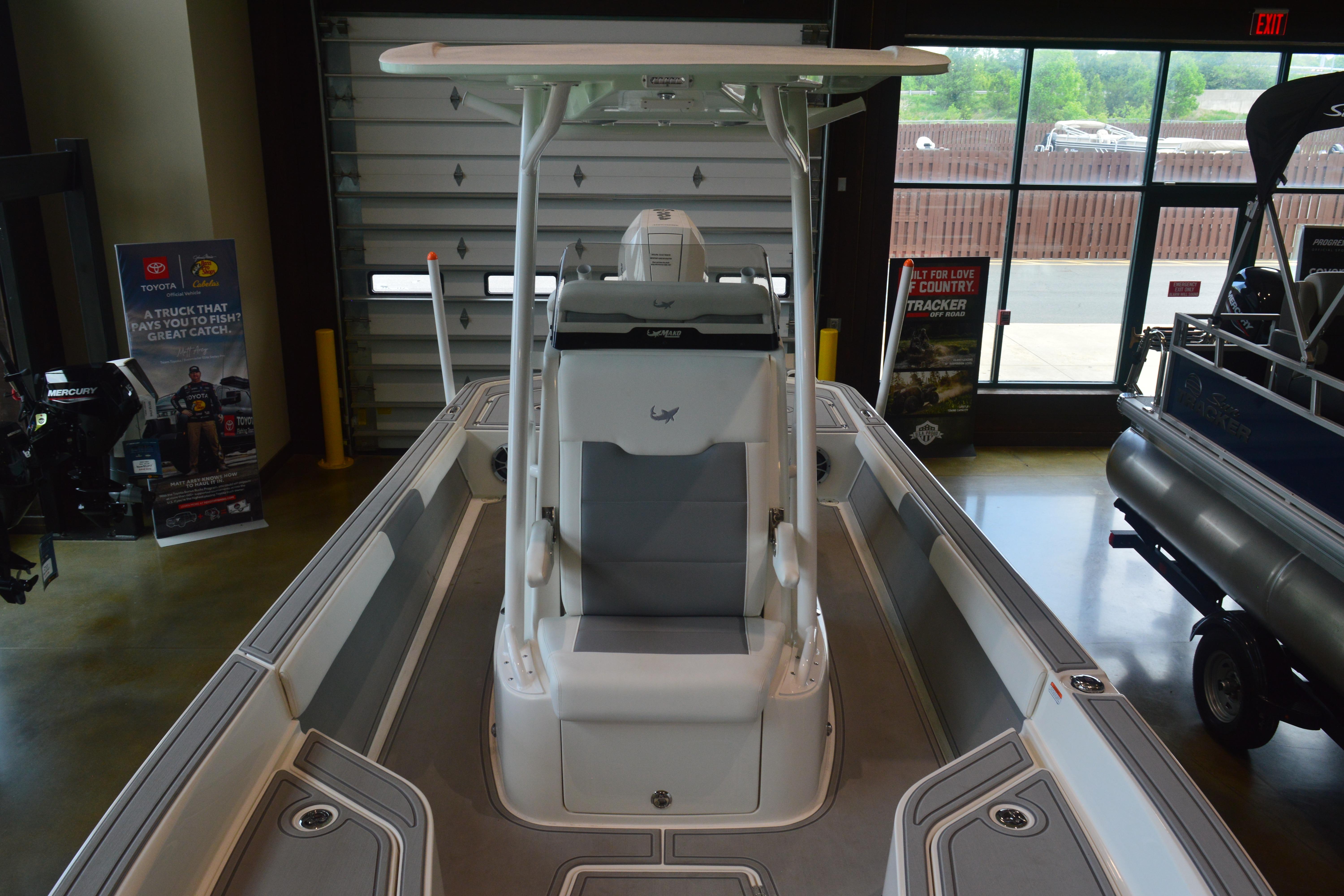 2026 Mako 24 APEX boat interior with seating and console in showroom.