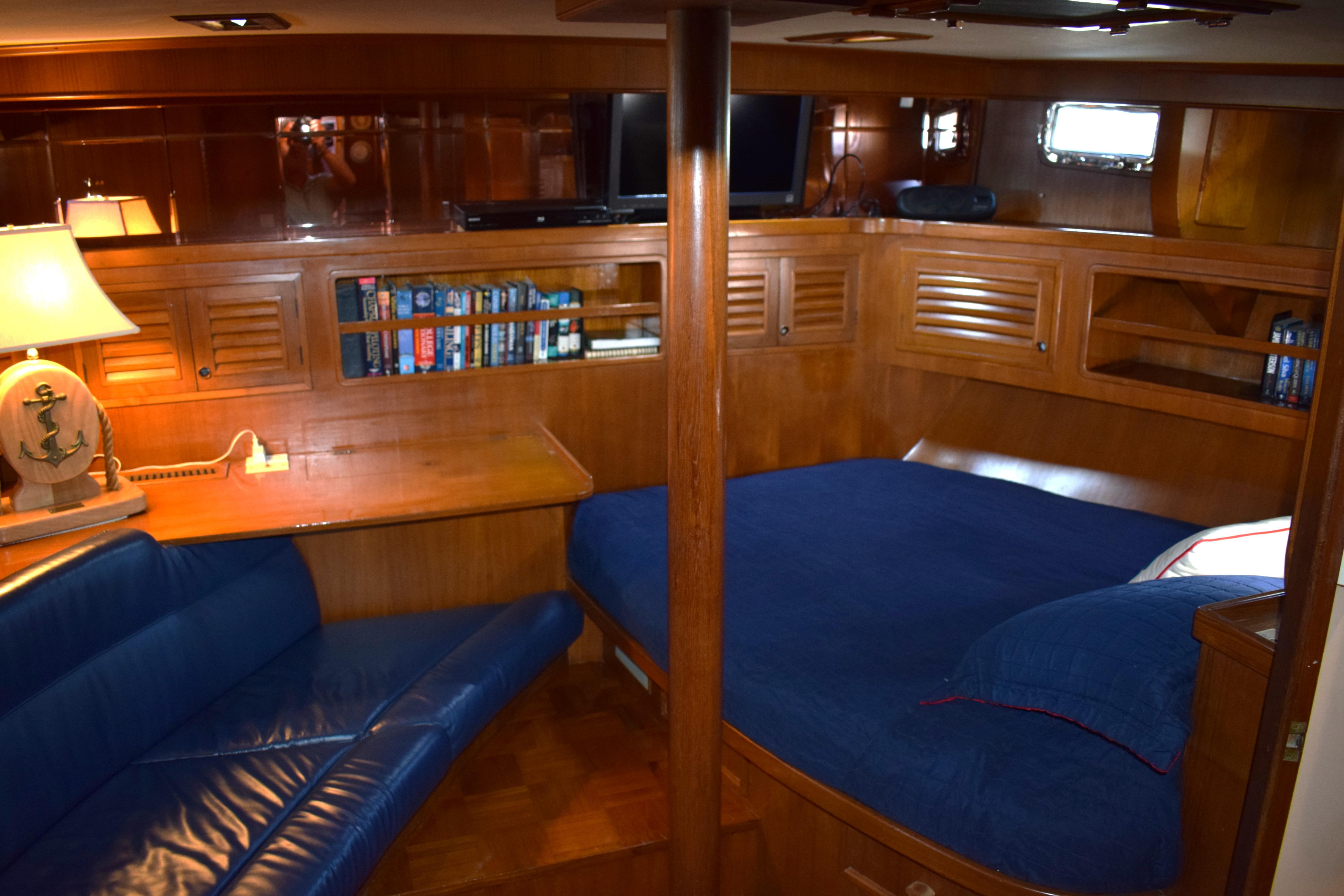 Luxurious 1980 Cheoy Lee 52 Motorsailer interior with cozy seating, bed, and wooden cabinetry.