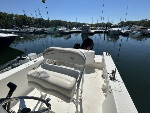 The image shows the cockpit of an Aquasport Osprey 250 boat in a marina.