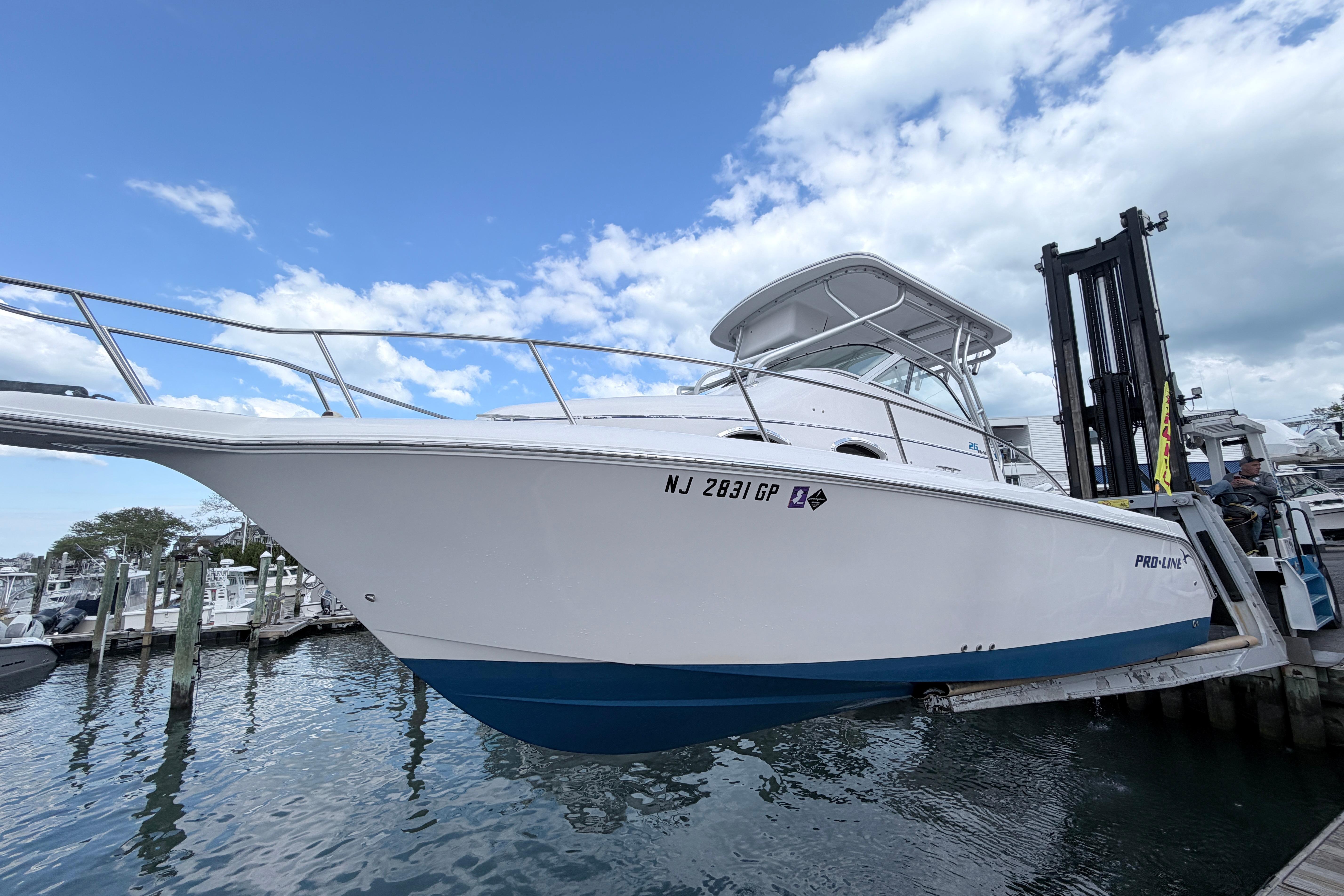 2001 Pro-Line 260 Walkaround boat lifted at marina, clear sky background.