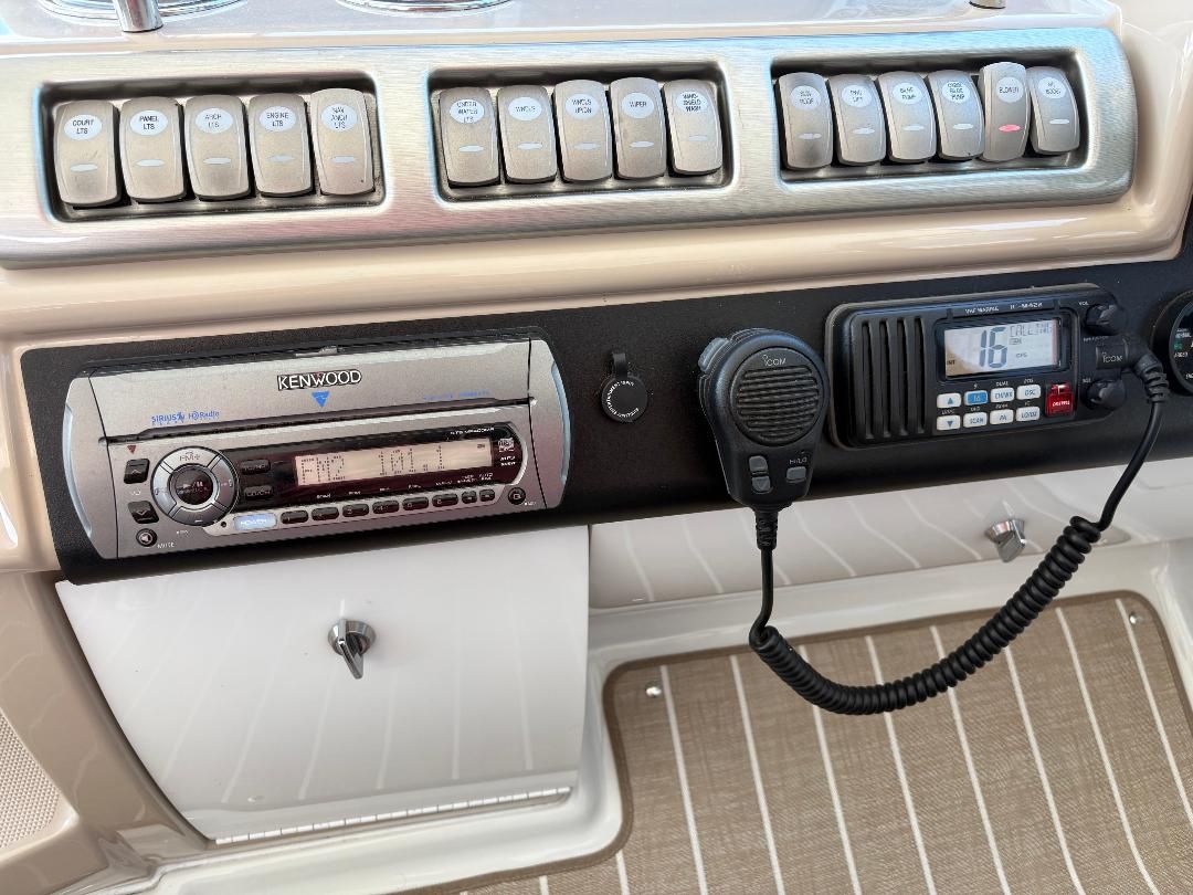 The image shows a boat dashboard with a Kenwood radio and a communication device.