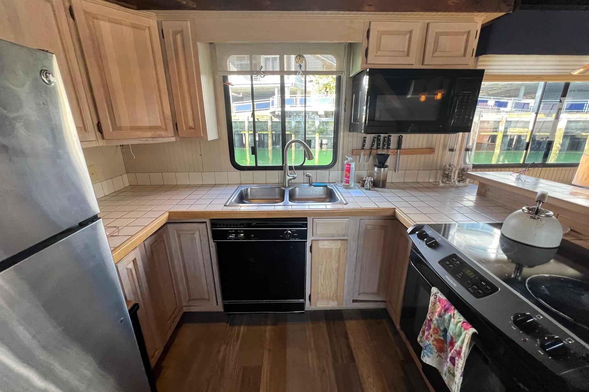 1993 Sumerset houseboat kitchen with wooden cabinets, stainless steel appliances, and tiled countertops.