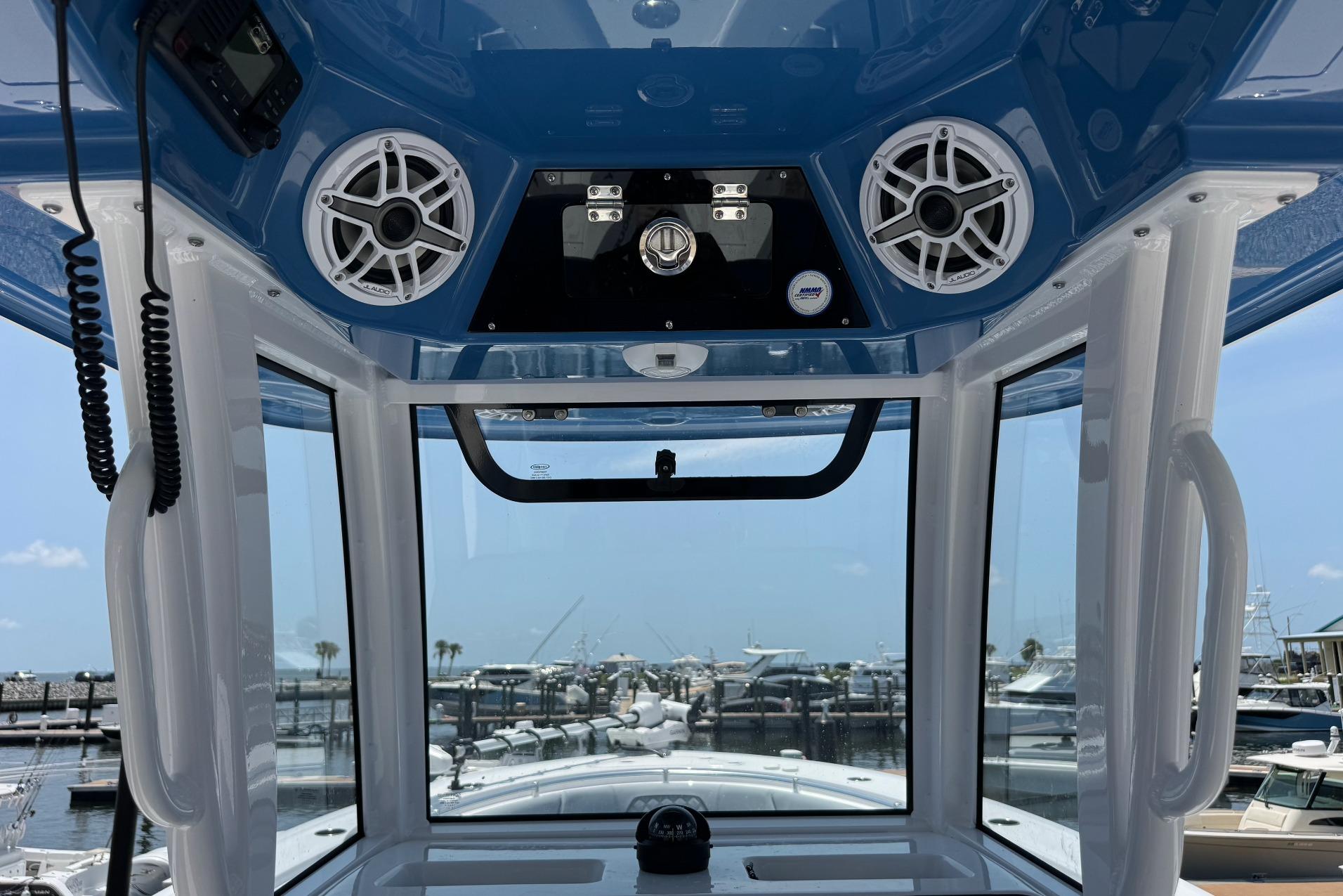 Interior view of 2026 Sportsman Open 262 Center Console boat with speakers and marina background.