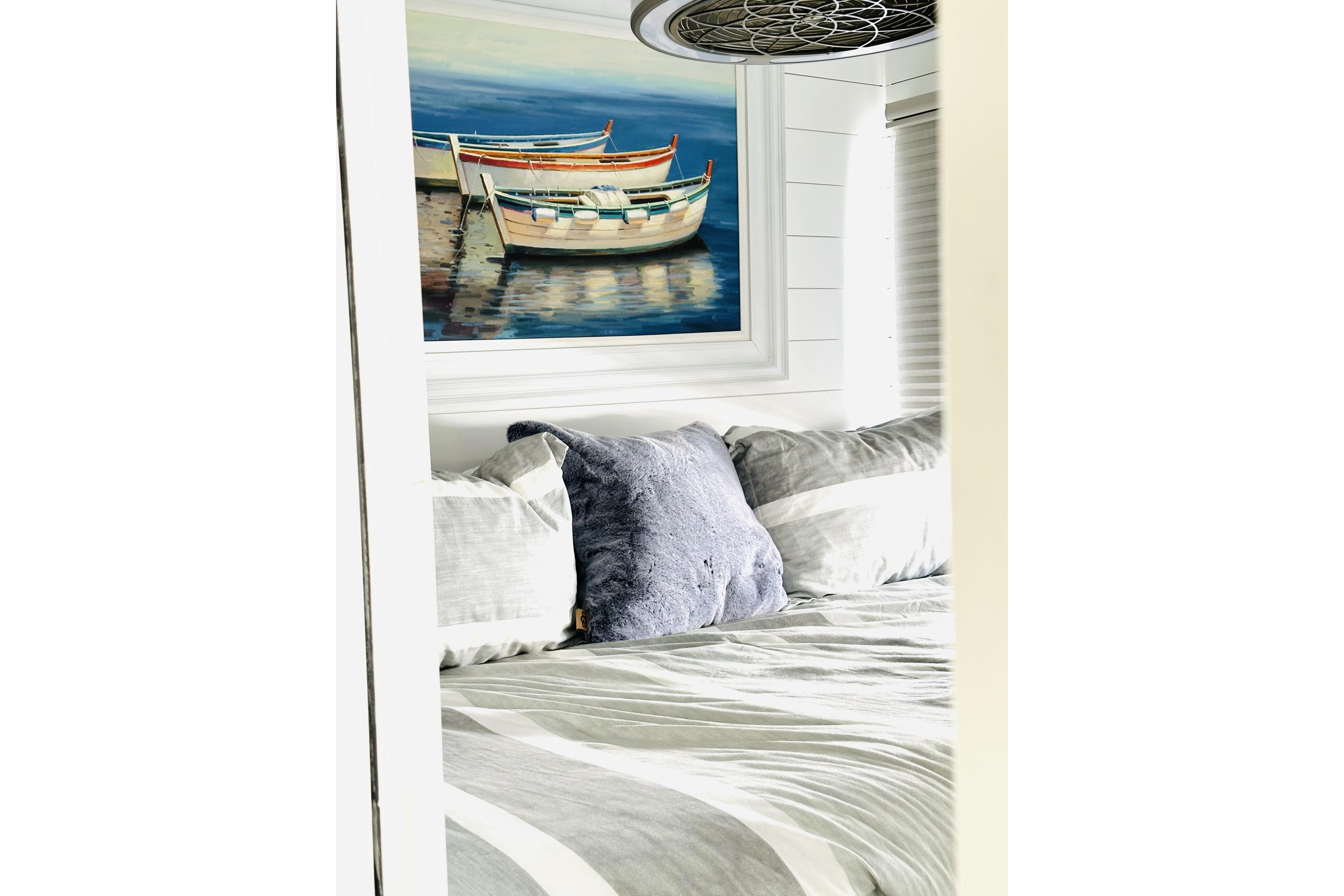 Cozy bedroom in 1992 Sumerset 66 houseboat with nautical painting and plush pillows.