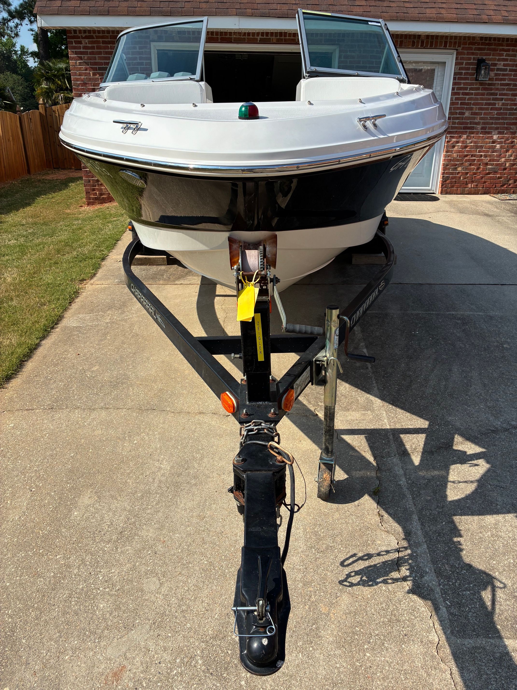 A 2012 Chaparral 19 H2O Sport boat on a trailer in front of a garage.