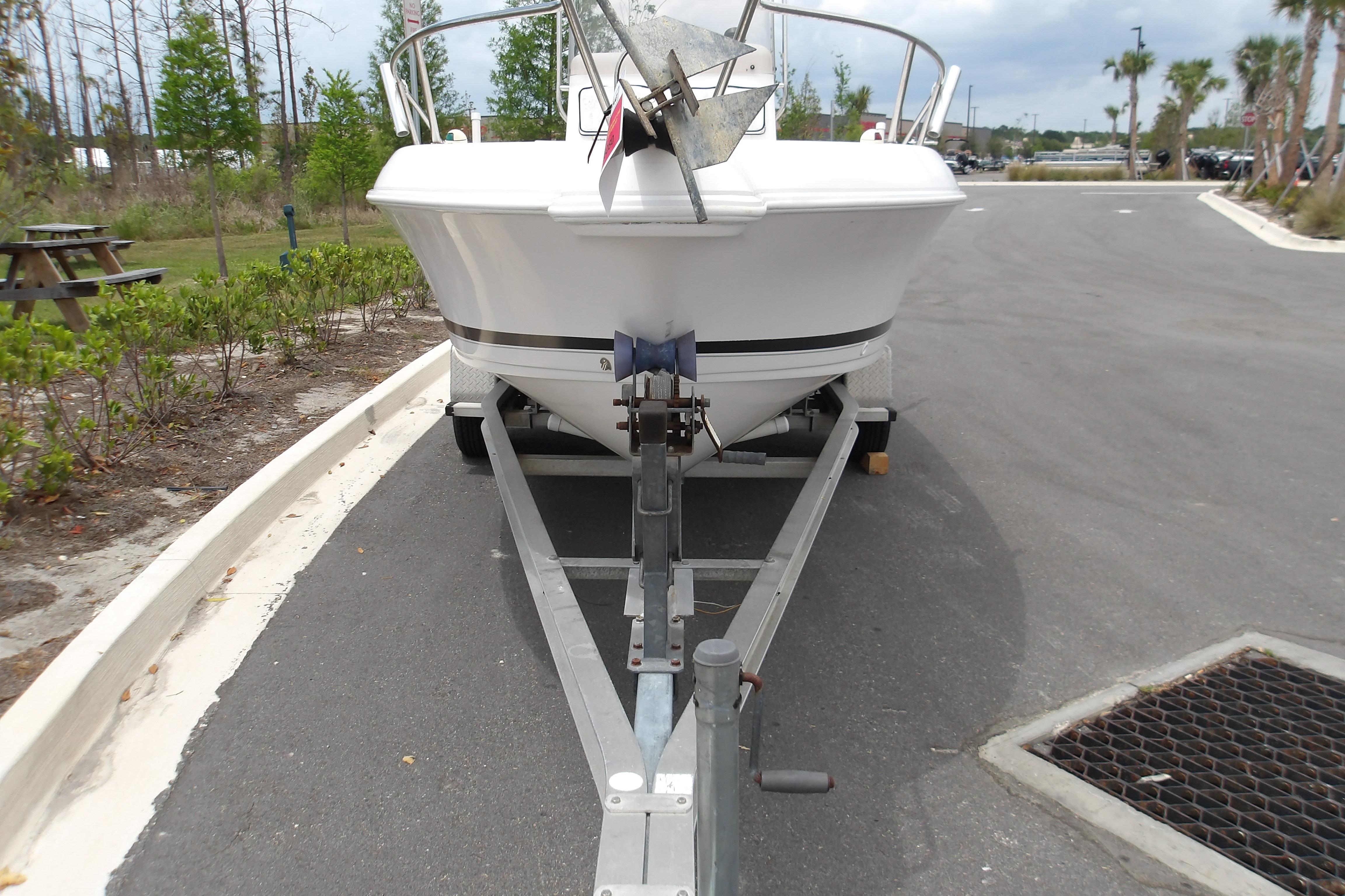 2000 Pro-Line 19 Sport boat on trailer in parking area, surrounded by greenery.