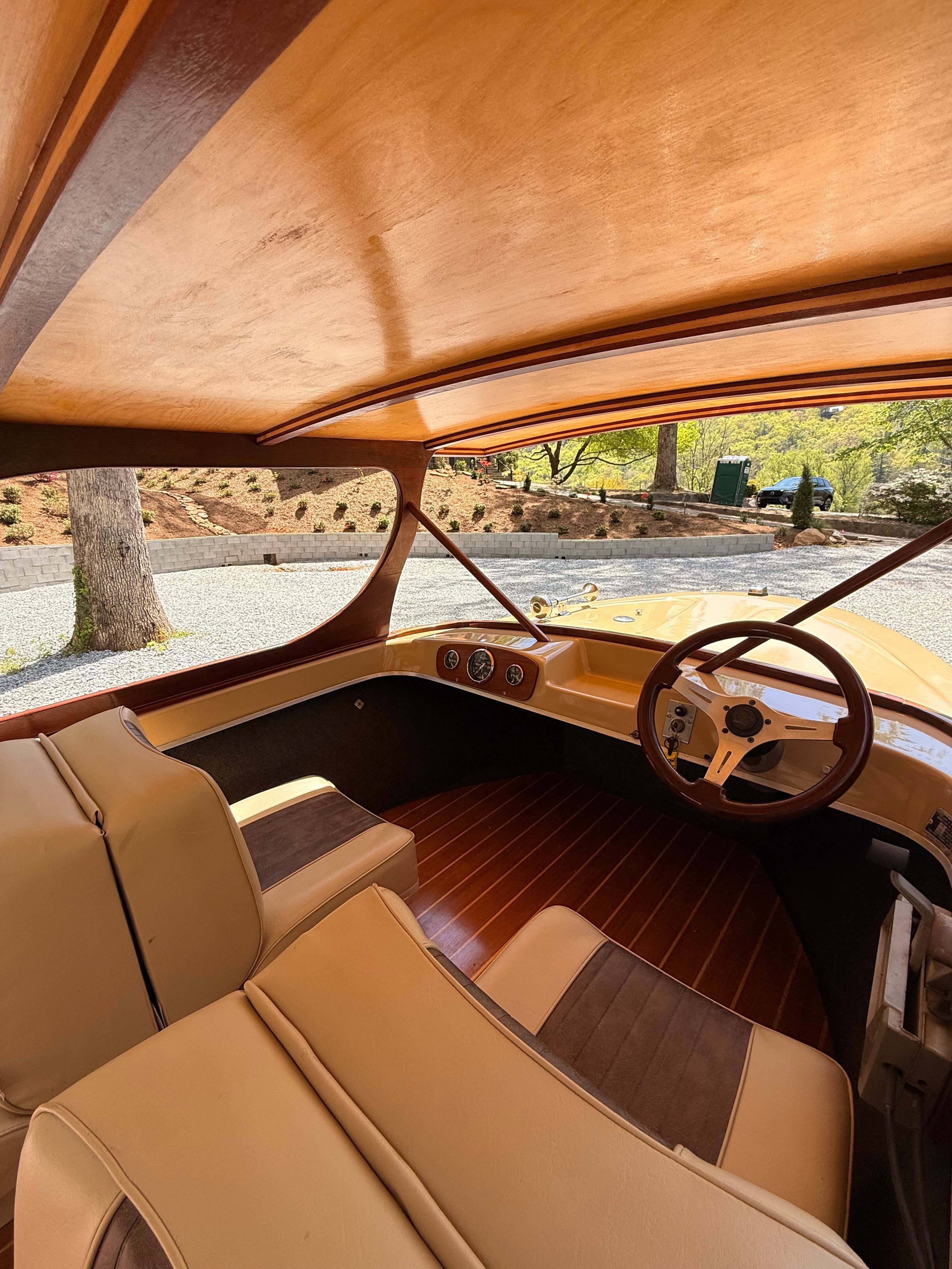 Interior view of a vintage boat with wood paneling and cream-colored seats.
