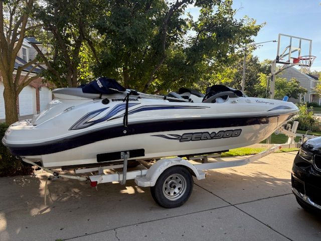 2004 Bombardier Sea-Doo Challenger boat on trailer, parked in driveway.