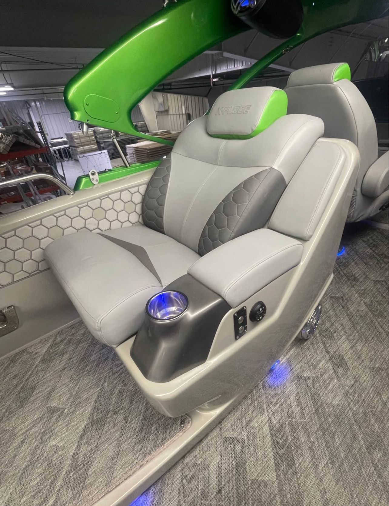 The 2020 Manitou 27 X-Plode SHP seat is gray with green accents and a cup holder.
