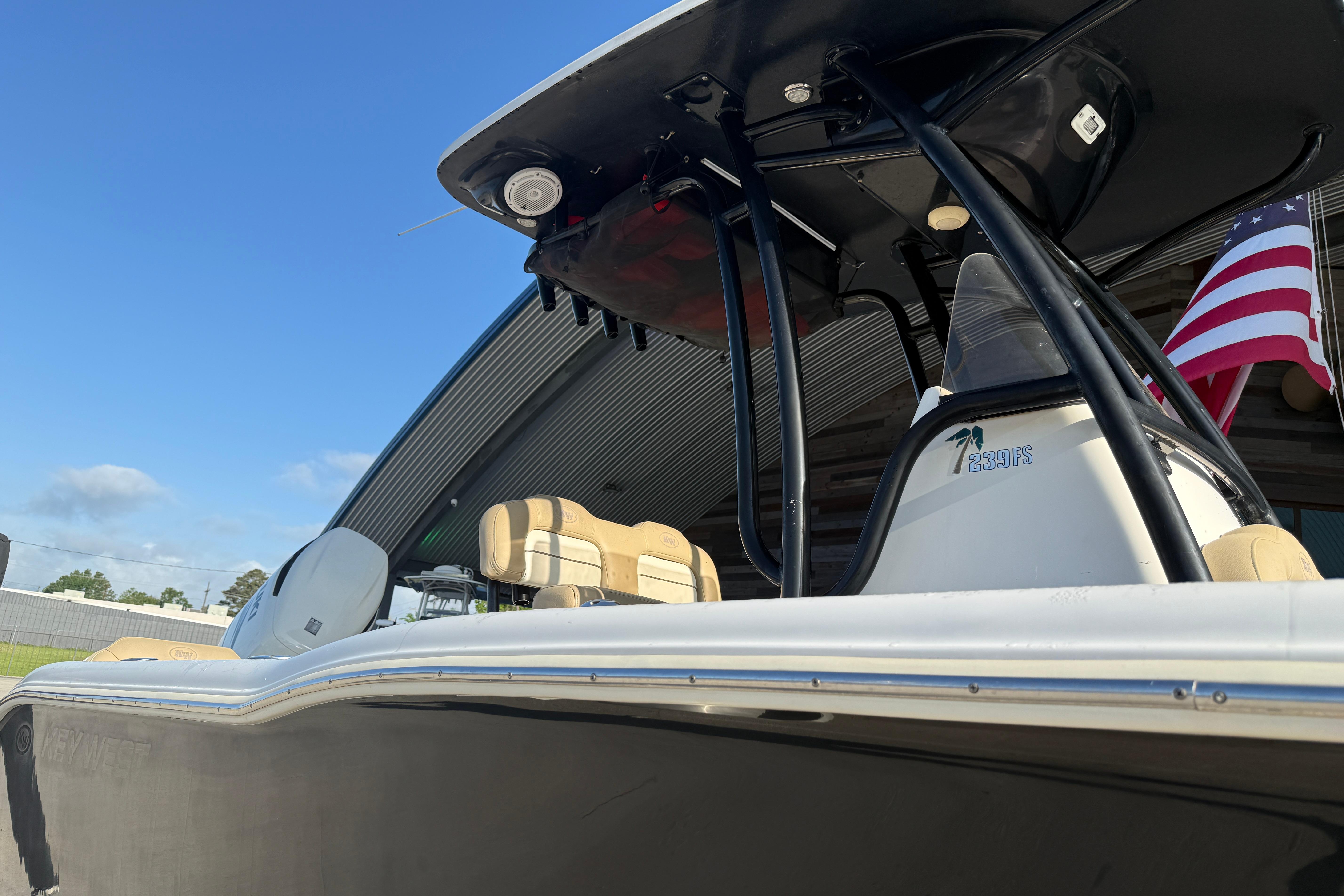2016 Key West 239 FS boat with American flag, under clear blue sky.