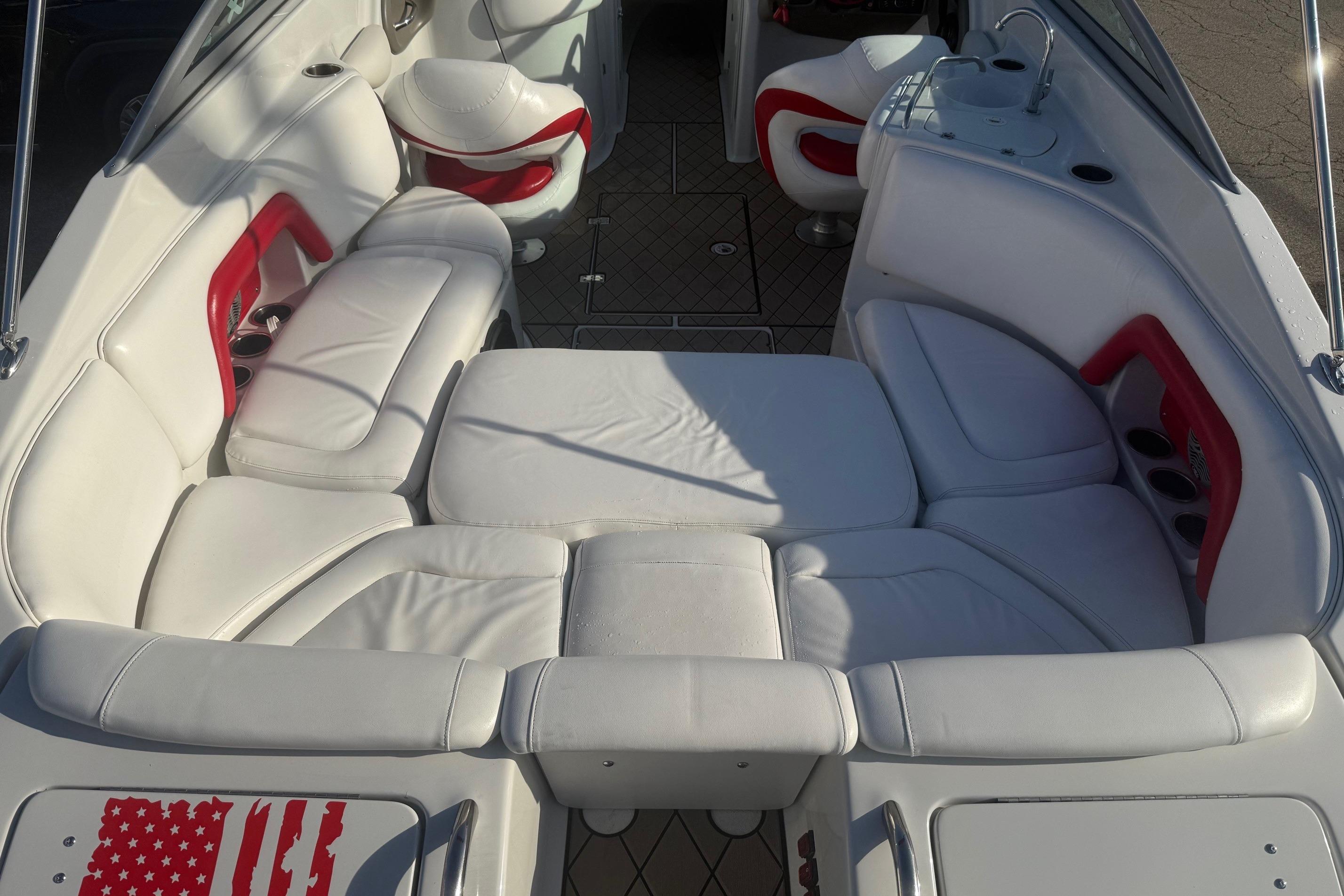 2005 Crownline 270 BR boat interior with white and red seating, cup holders, and sunlit upholstery.