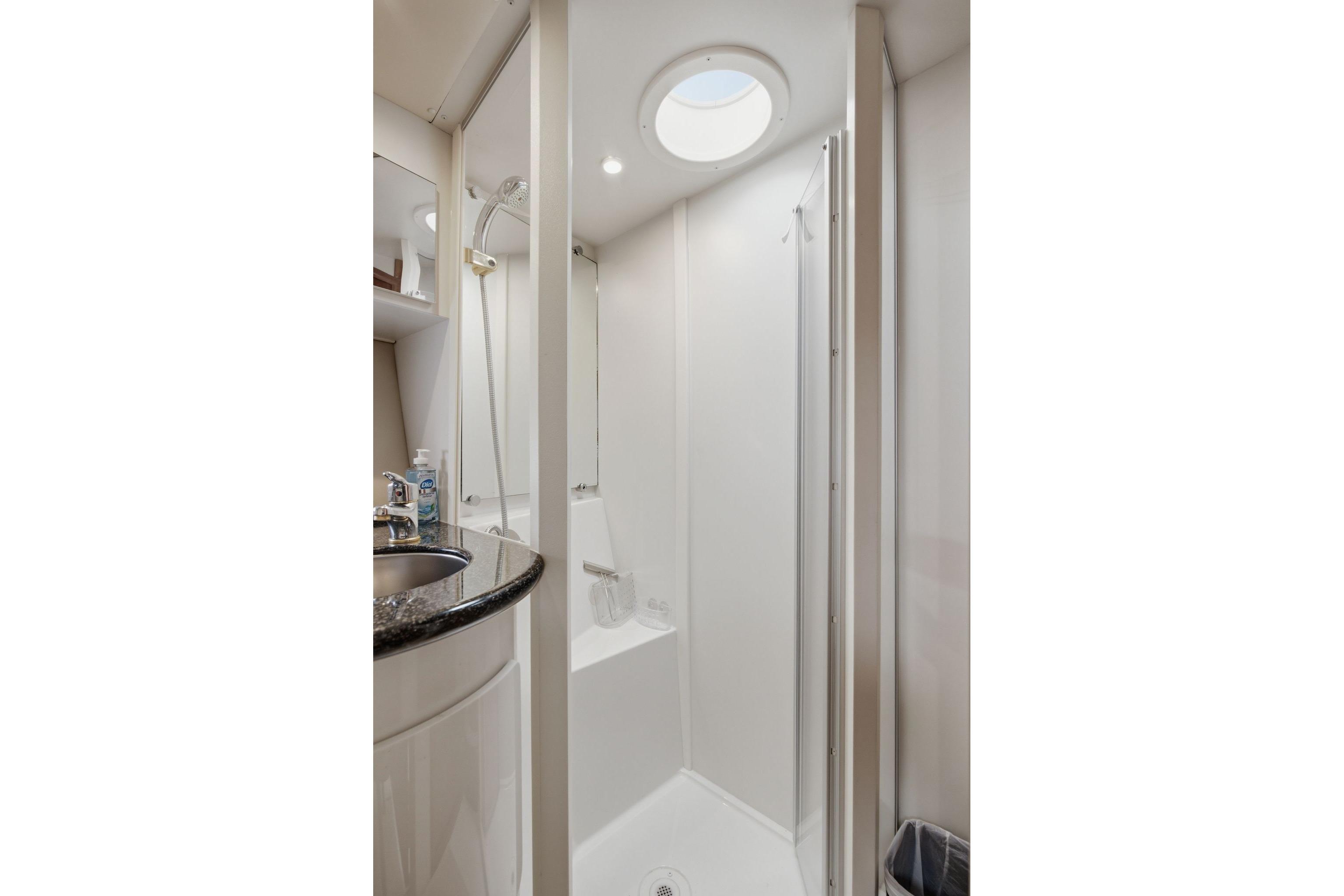 2005 Carver 39 Motor Yacht bathroom with shower, sink, and circular skylight.