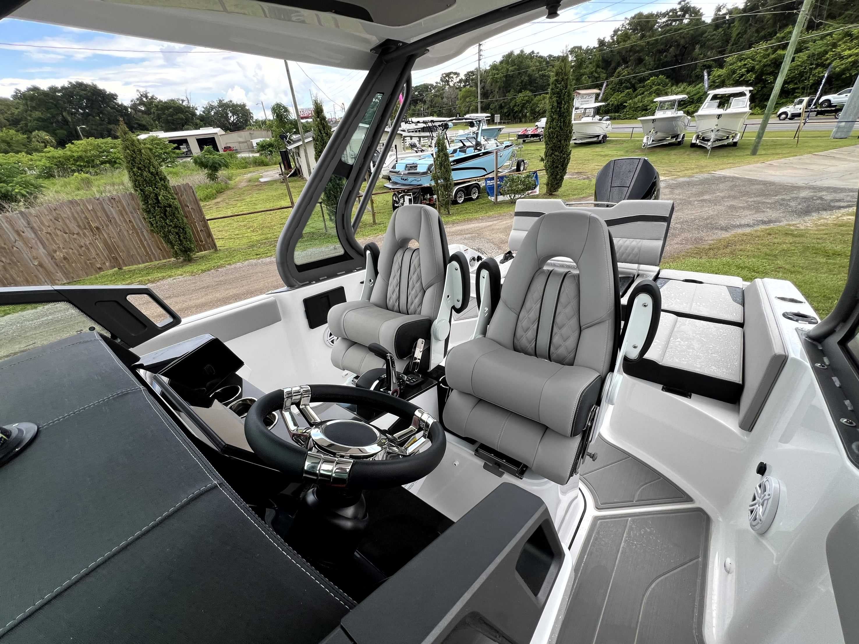 The image shows the cockpit of a Monterey Elite 25 boat with two cushioned seats and a modern helm.