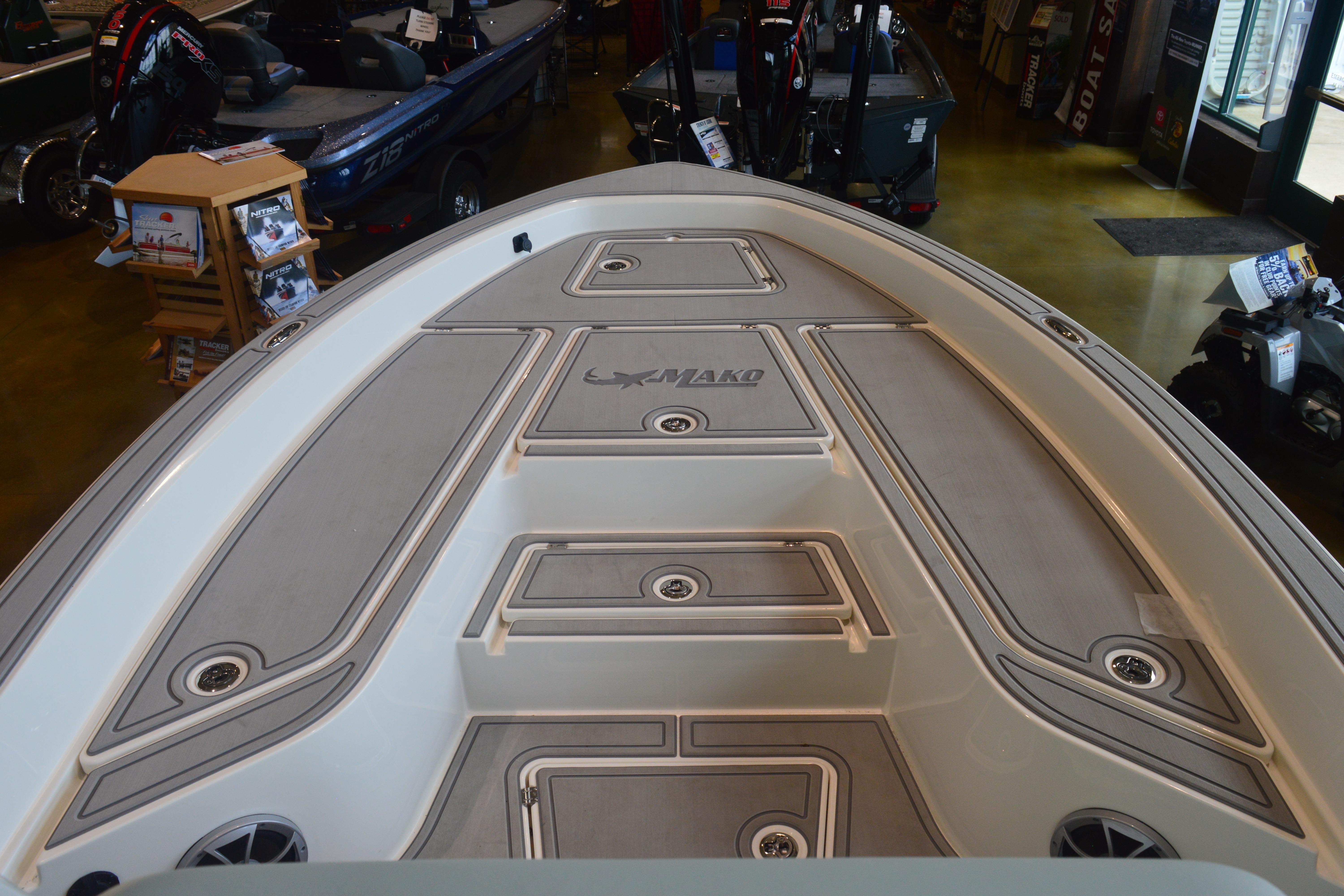 2026 Mako 24 APEX boat deck in showroom, showcasing sleek design and storage compartments.