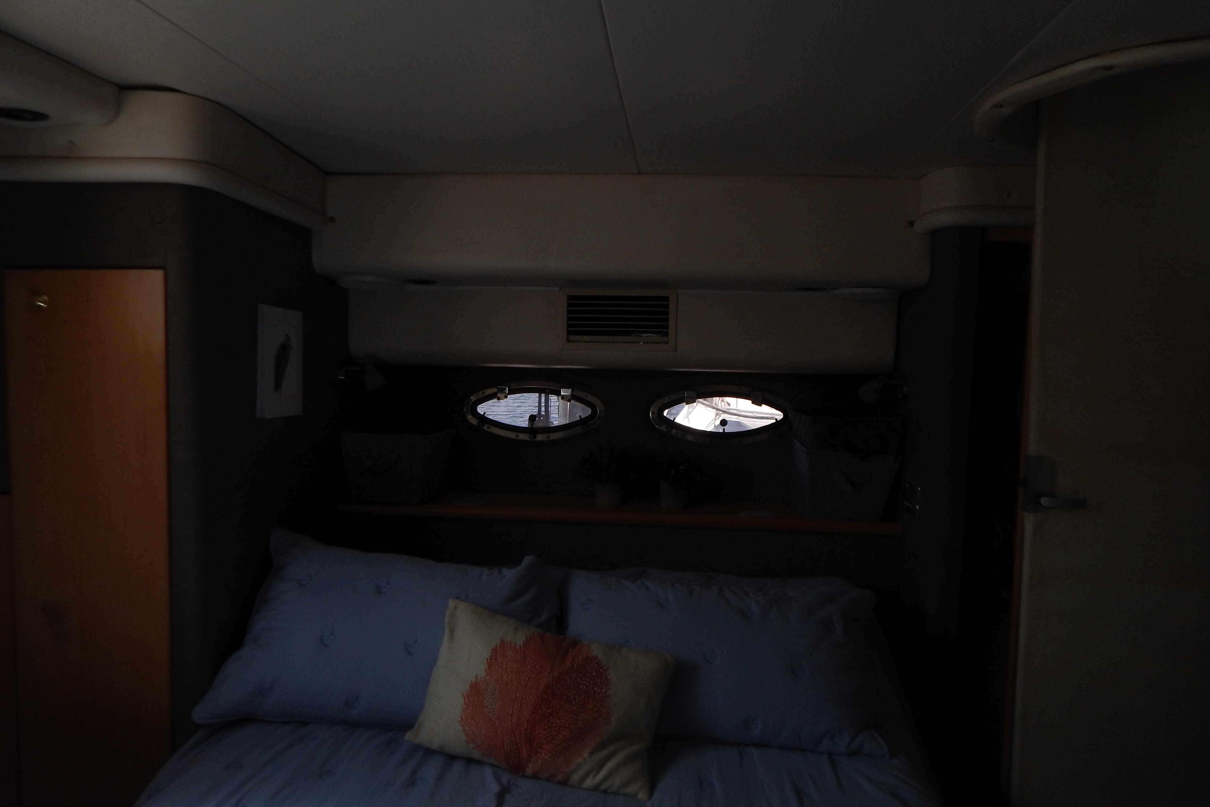 Interior cabin of a 1998 Magnum 4100 SCR yacht with bed and porthole windows.